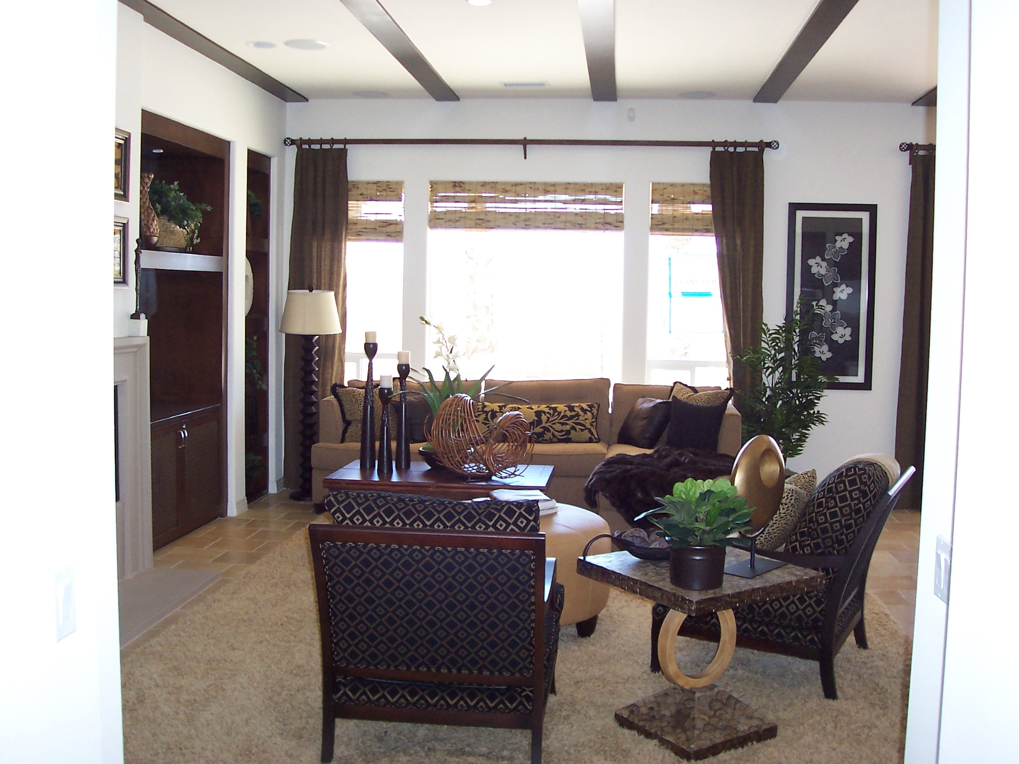 Living room with dark wood beams, patterned chairs and warm earth tones