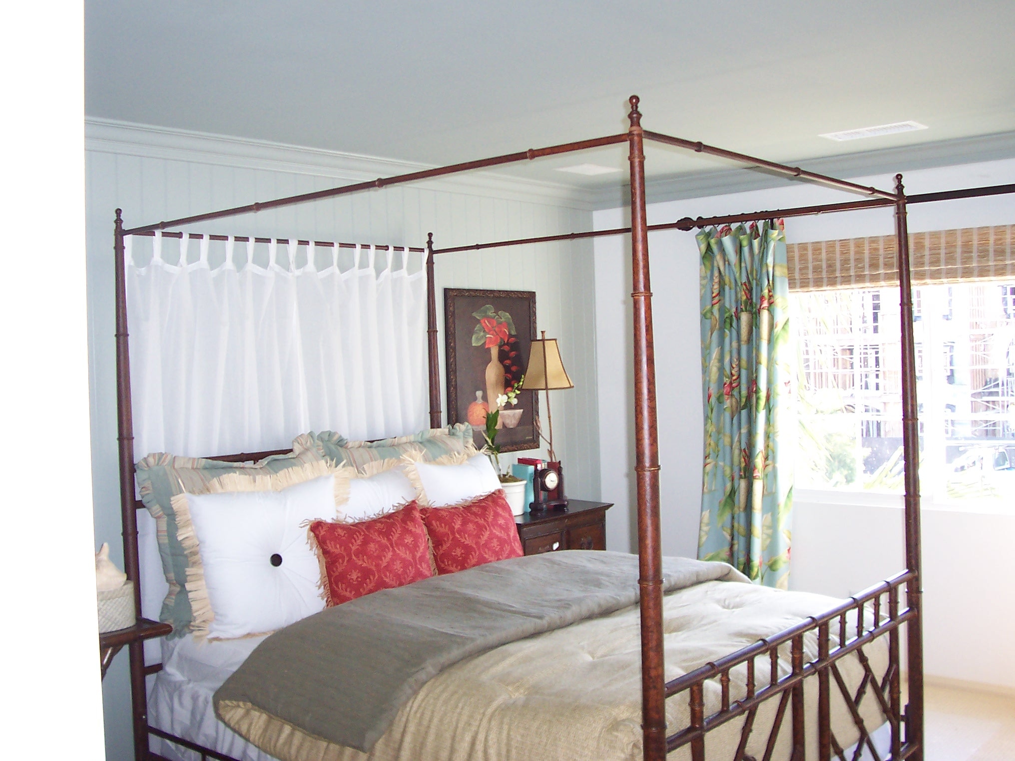 Four-poster bedroom with tropical curtains and layered bedding