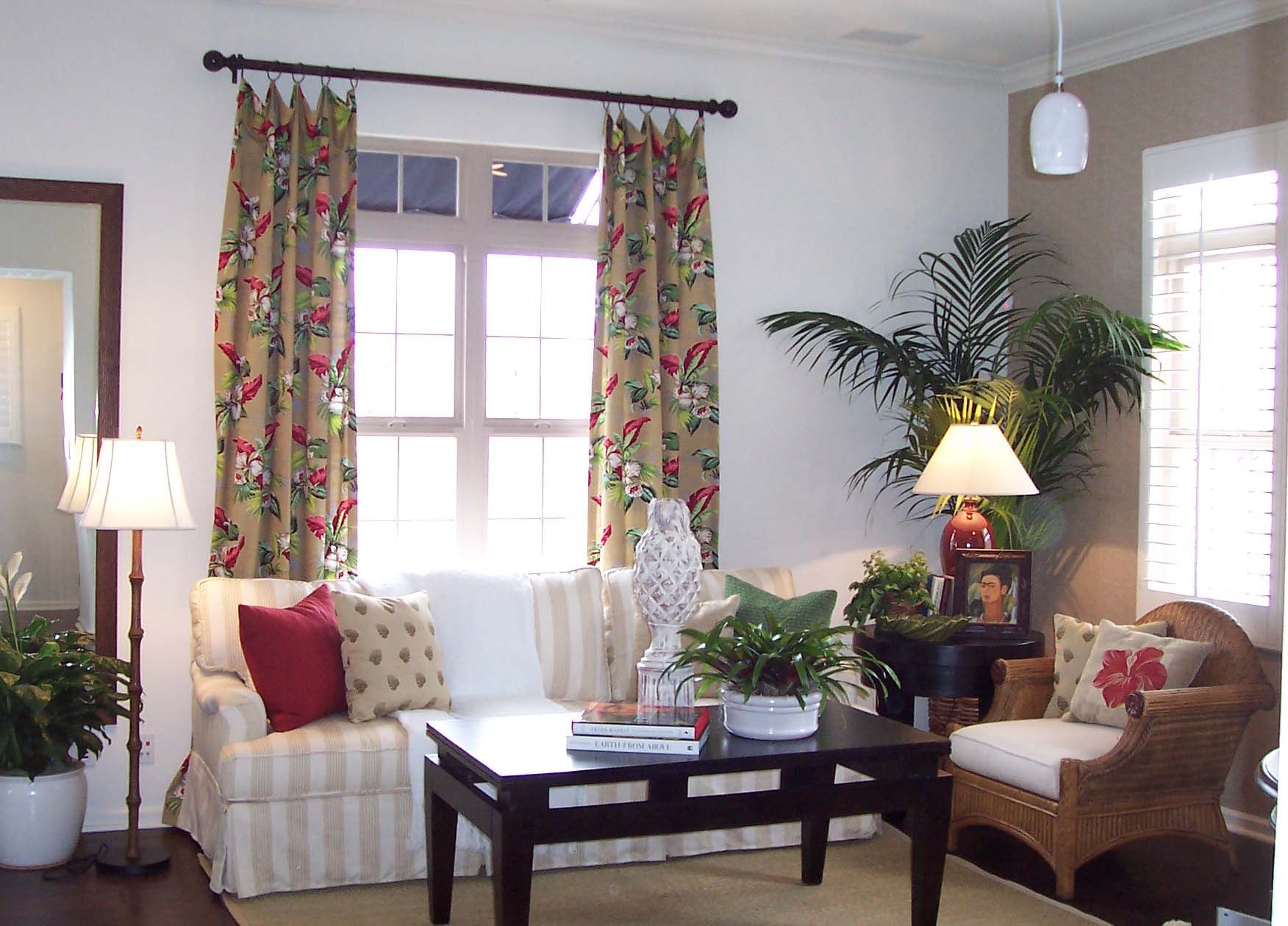 Tropical living room with floral curtains, wicker seating, and lush greenery