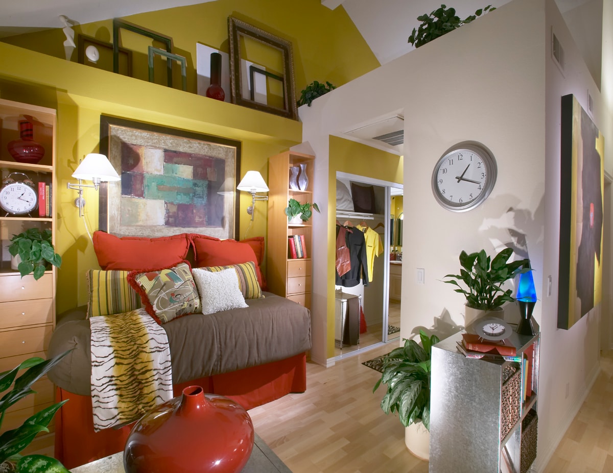 Colorful bedroom with yellow walls, red accents, and built-in shelving