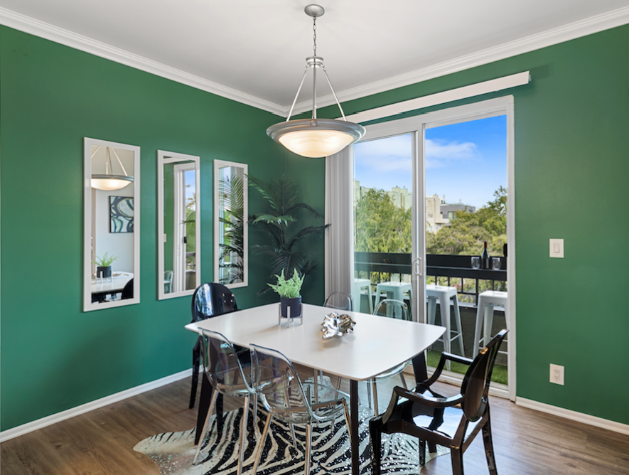 Emerald dining room with a white table, modern lighting, and balcony view