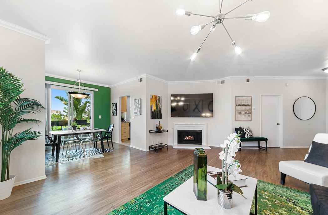 Open-plan living and dining room with emerald accents and contemporary furnishings
