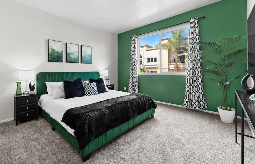 Secondary bedroom with an emerald upholstered bed and graphic black accents