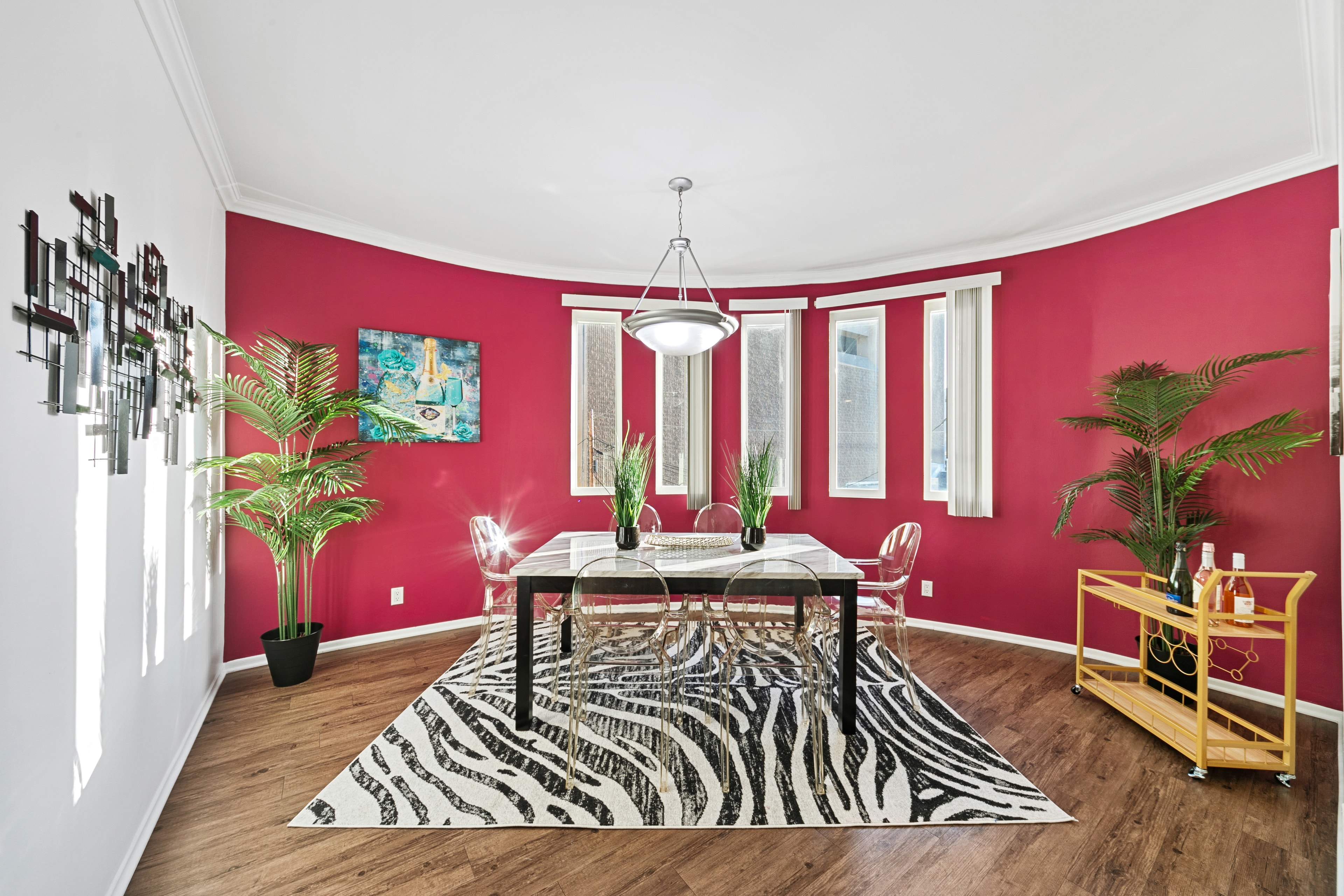 Fuchsia dining room with zebra rug, clear chairs, and tropical plants