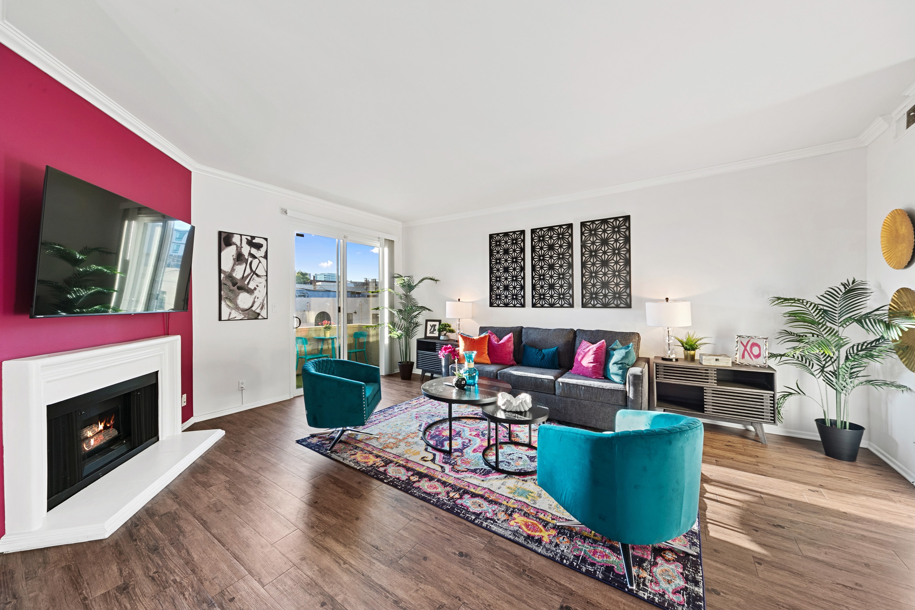 Living room with fuchsia fireplace wall, teal chairs, and graphic black wall art