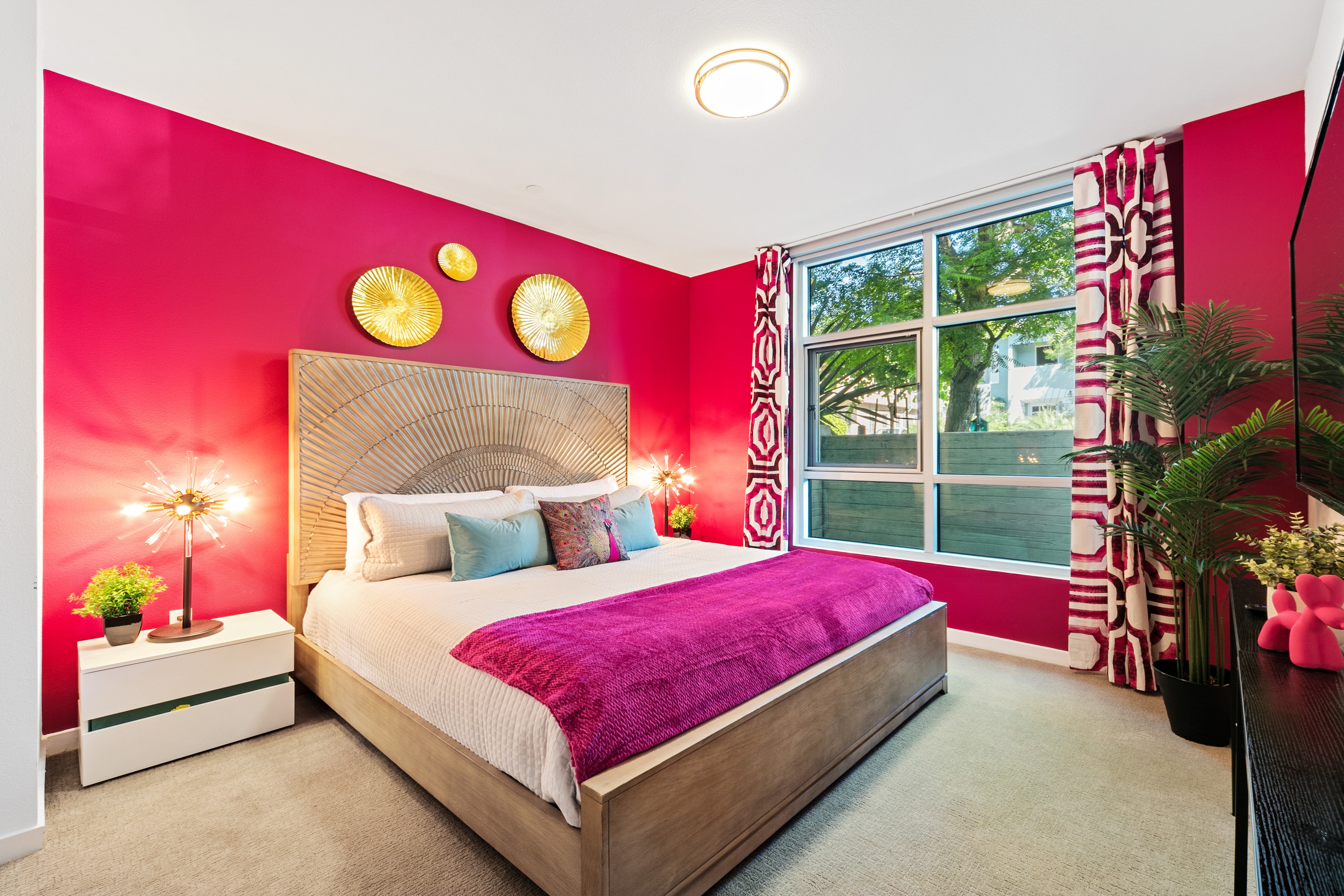 Fuchsia primary bedroom with a sunburst headboard and layered textiles