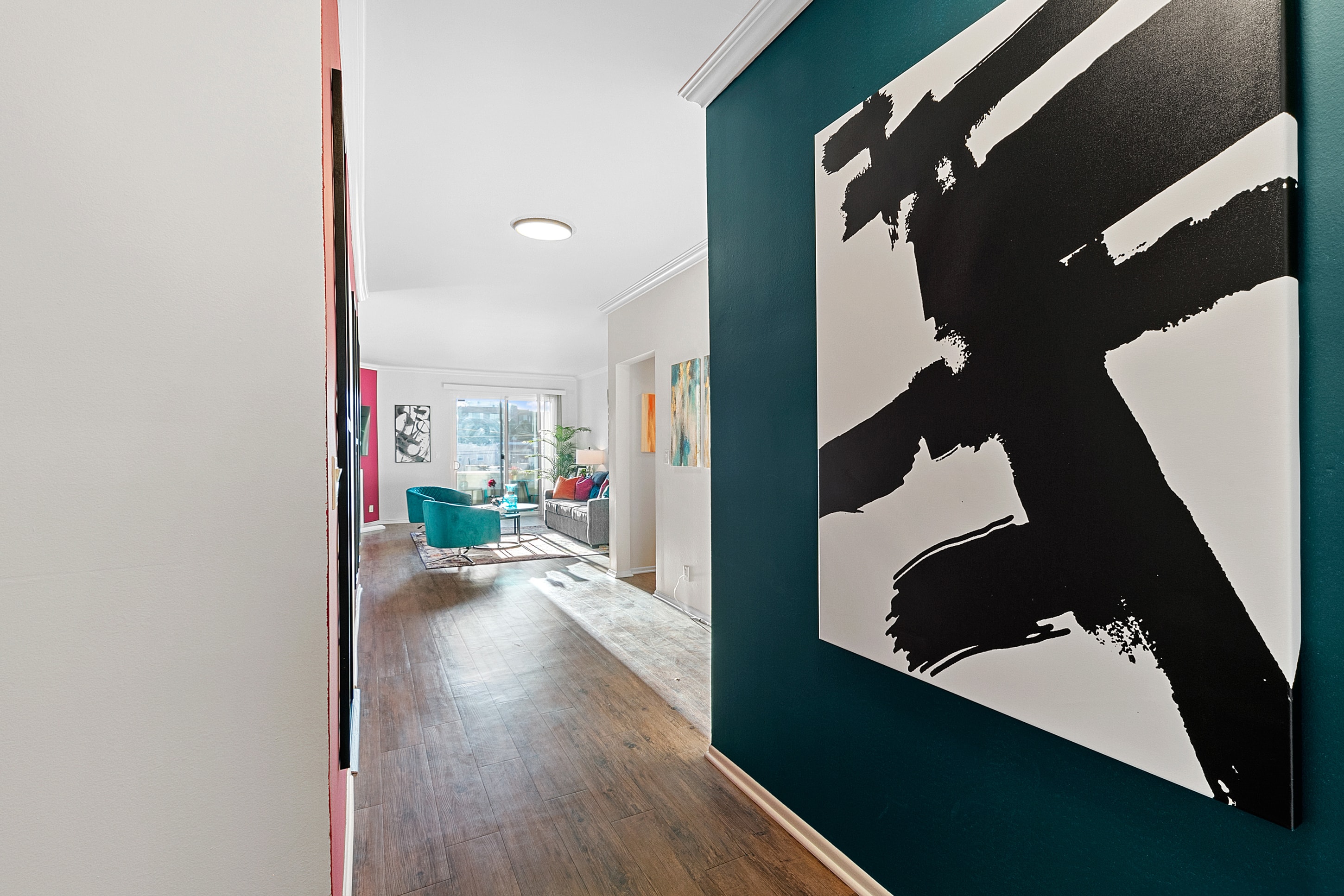 Teal entry hallway with bold black-and-white artwork leading to a colorful living room