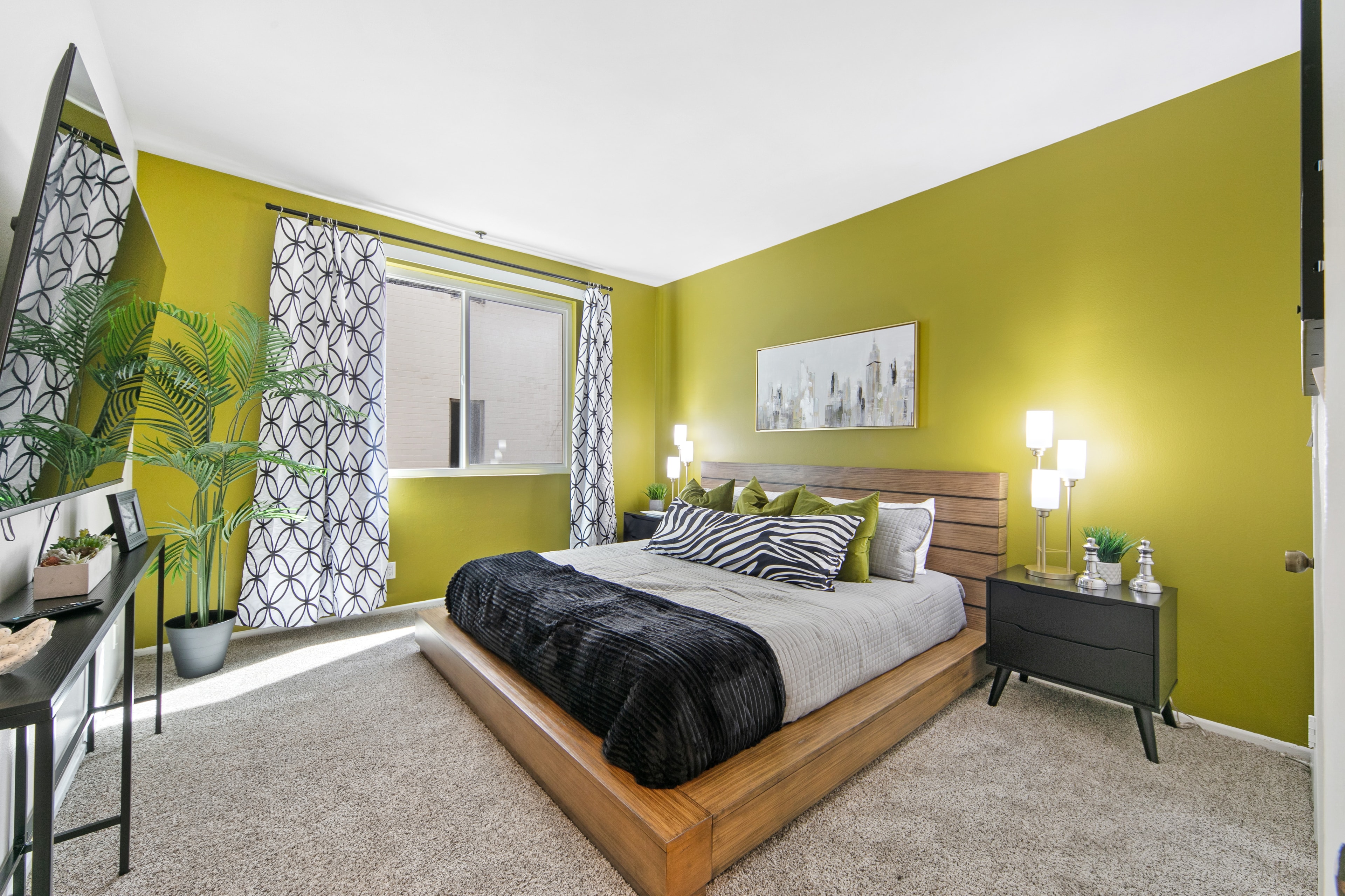 Bedroom with kiwi-green walls, a wood platform bed, and black-and-white textiles