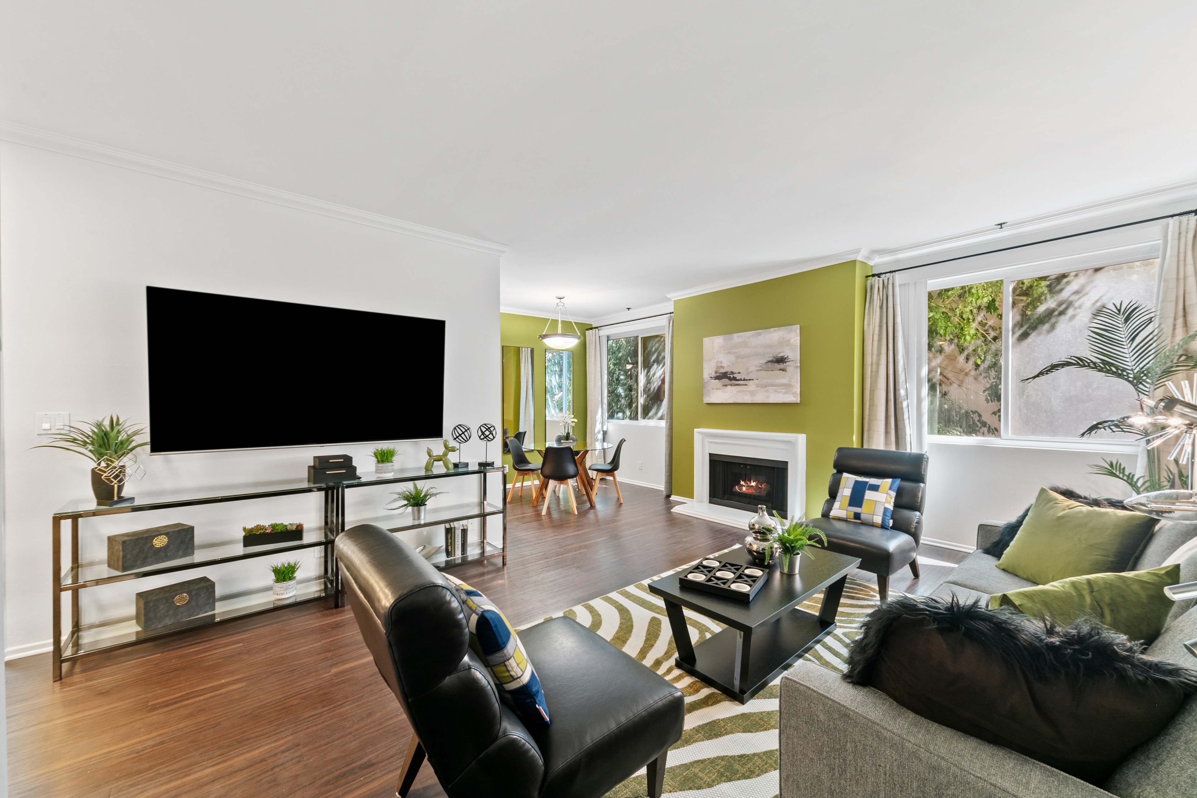 Open-plan living room with a television wall, kiwi-green fireplace, and dining area