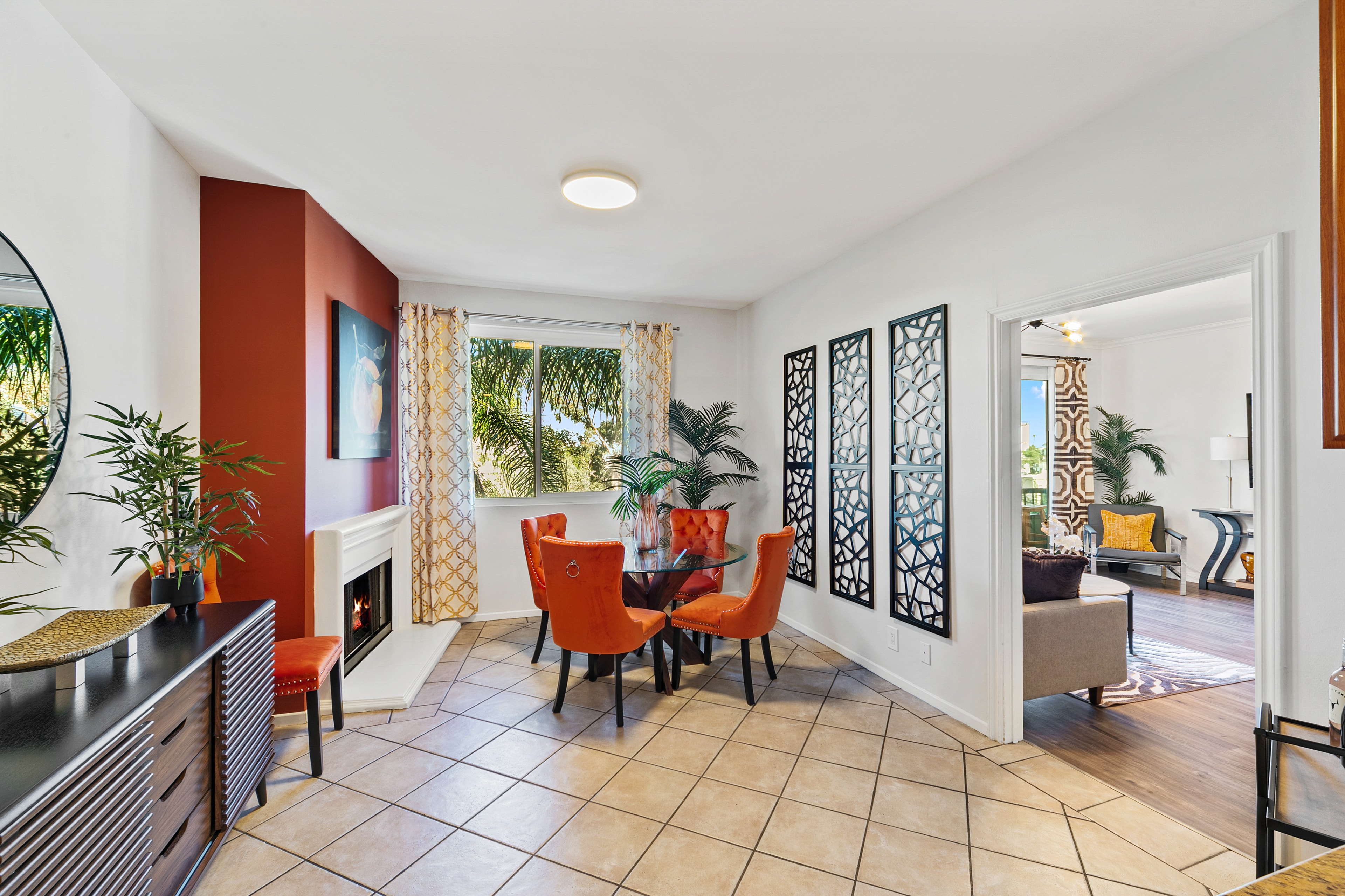 Dining room with sienna accent wall, glass table, and orange chairs