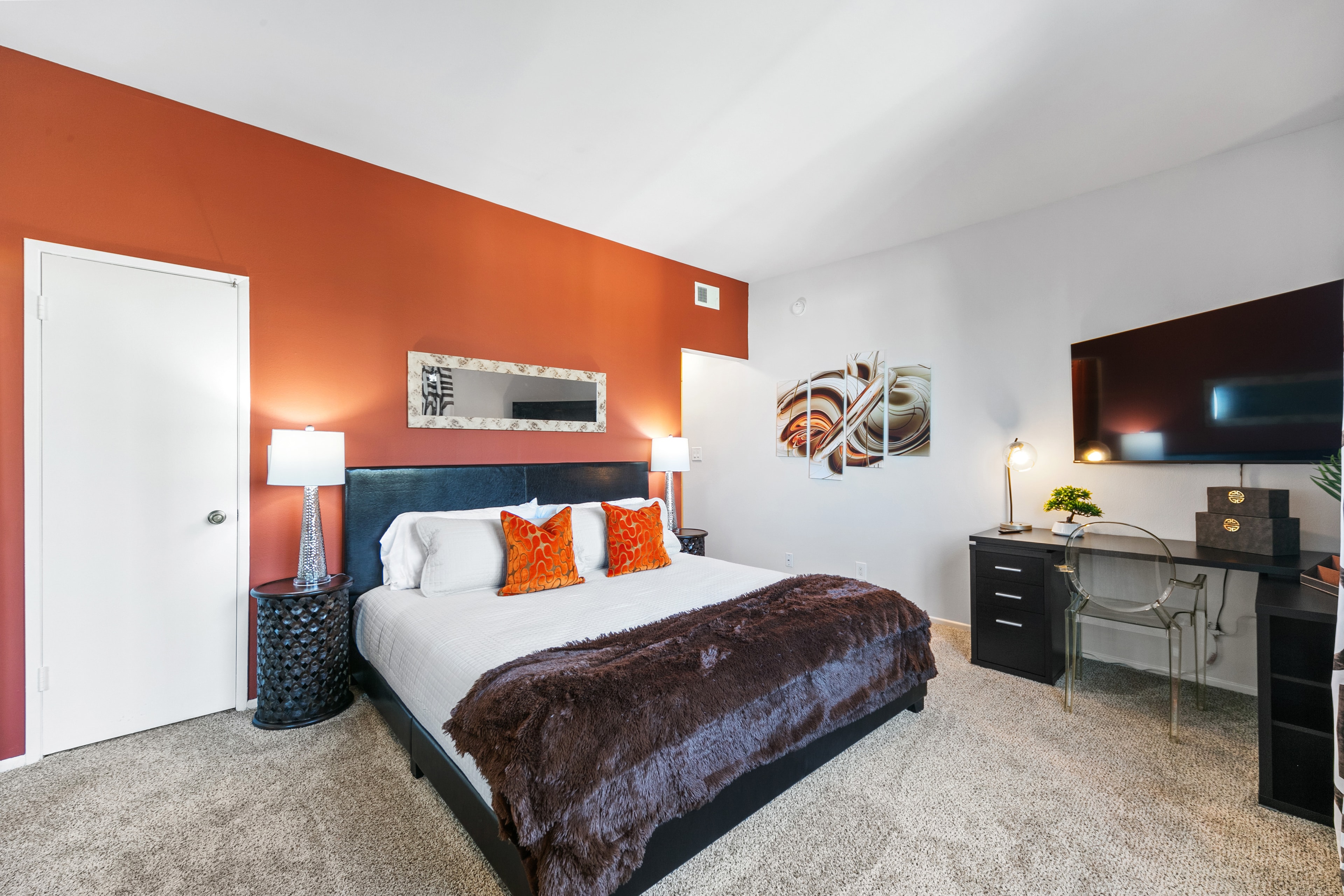 Secondary bedroom with a sienna accent wall and tailored furnishings