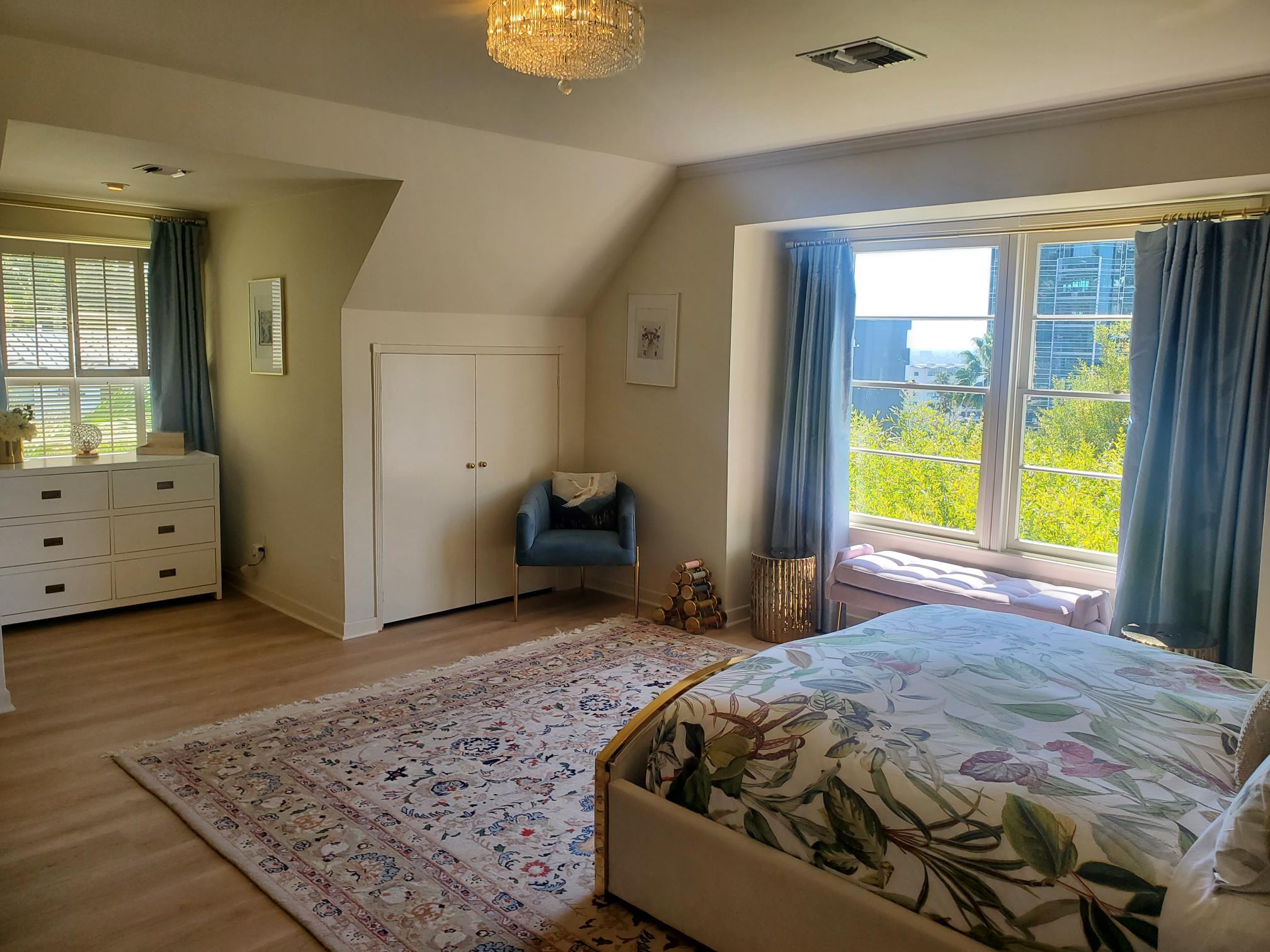 Primary bedroom with botanical bedding, blue curtains, and gold accents