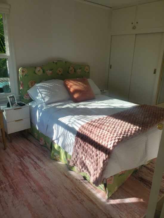 Sunlit guest bedroom with floral upholstered bed and blush throw