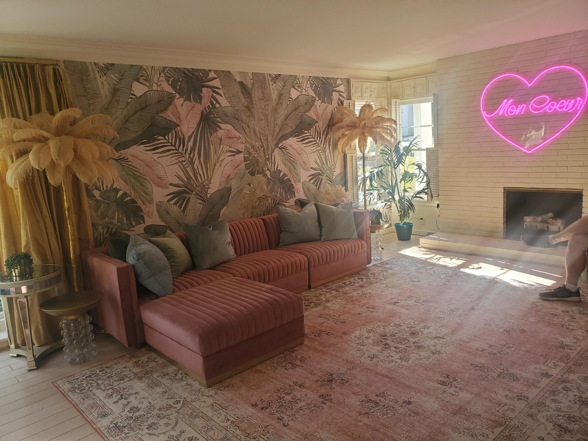 Living room with blush sectional, white brick fireplace, and pink neon heart