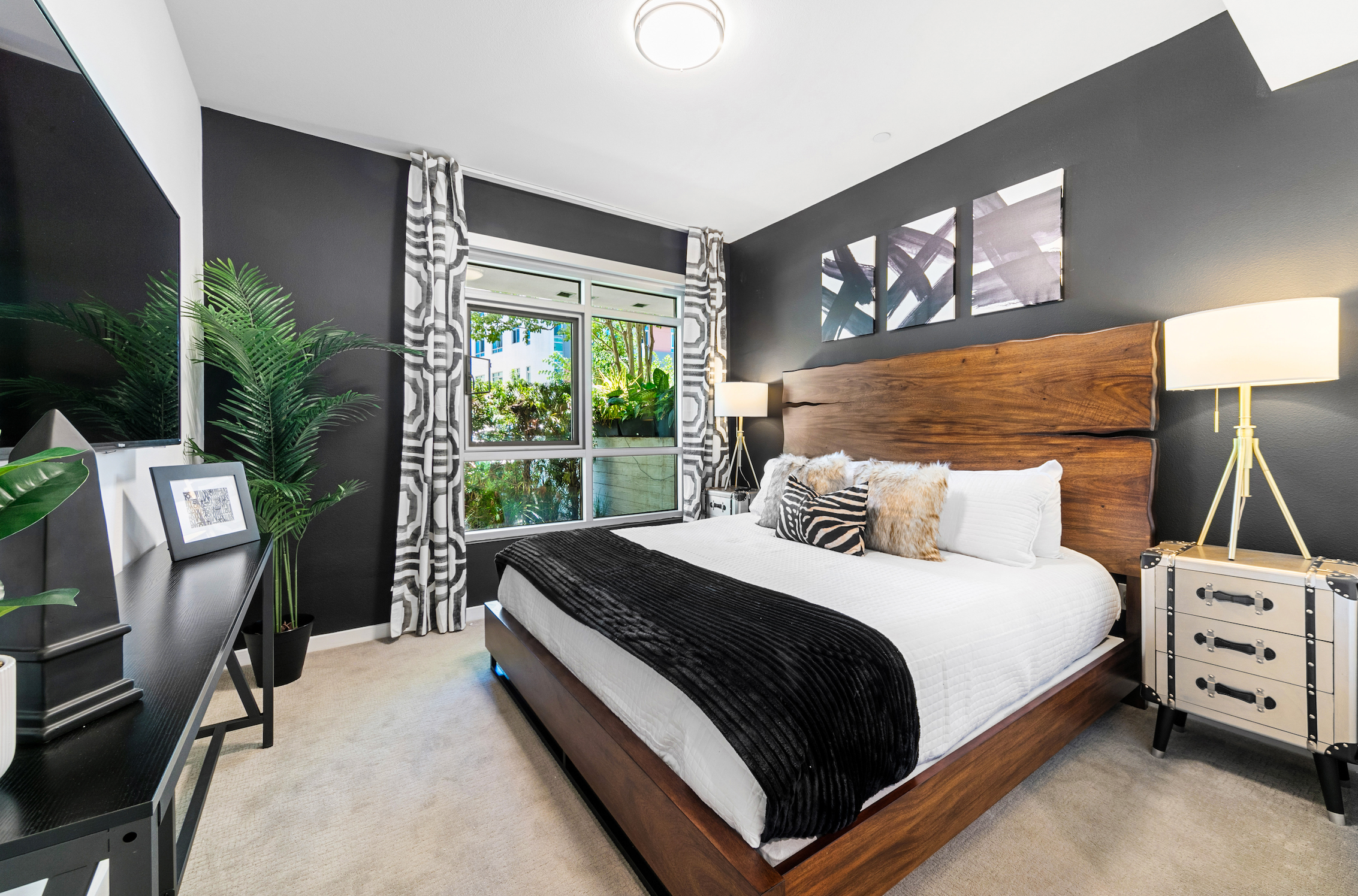 Bedroom with dark accent walls, wood bed, and graphic textiles