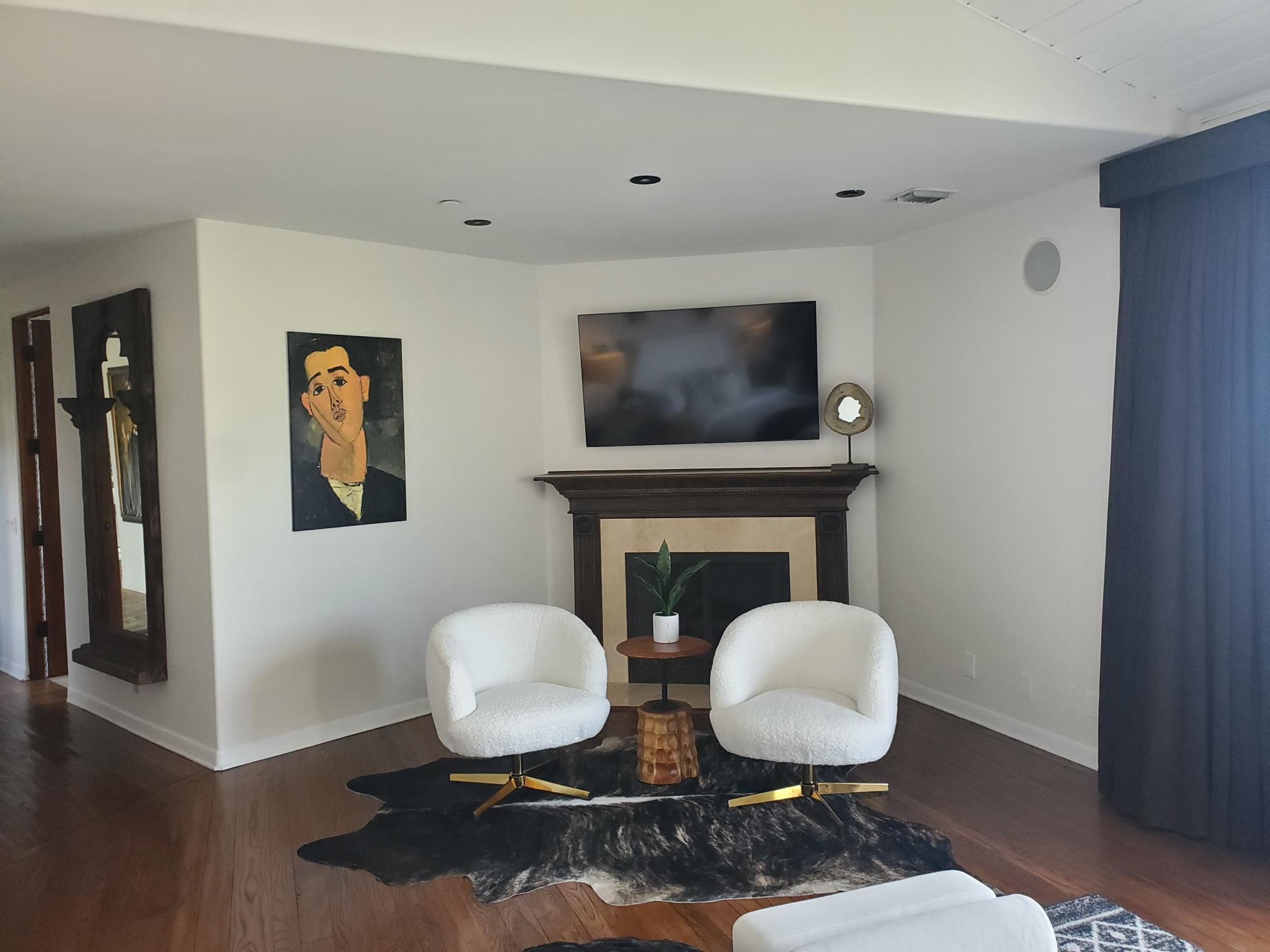 Fireplace sitting room with white boucle chairs, dark wood floors, and blue curtains
