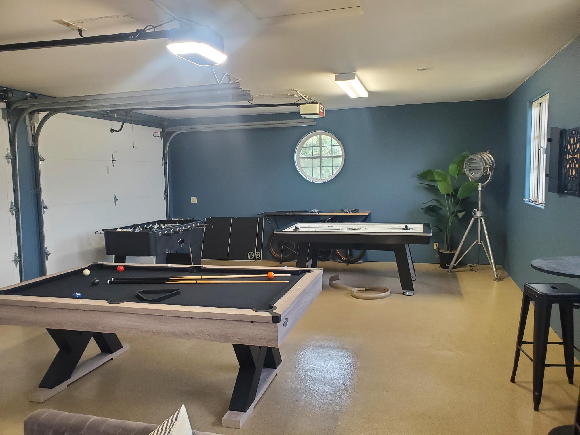 Garage game room with pool table, shuffleboard, foosball, and dartboard