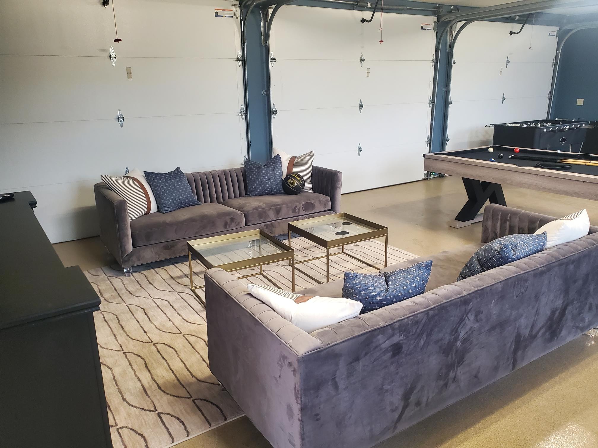 Garage lounge with velvet seating, pool table, and foosball table