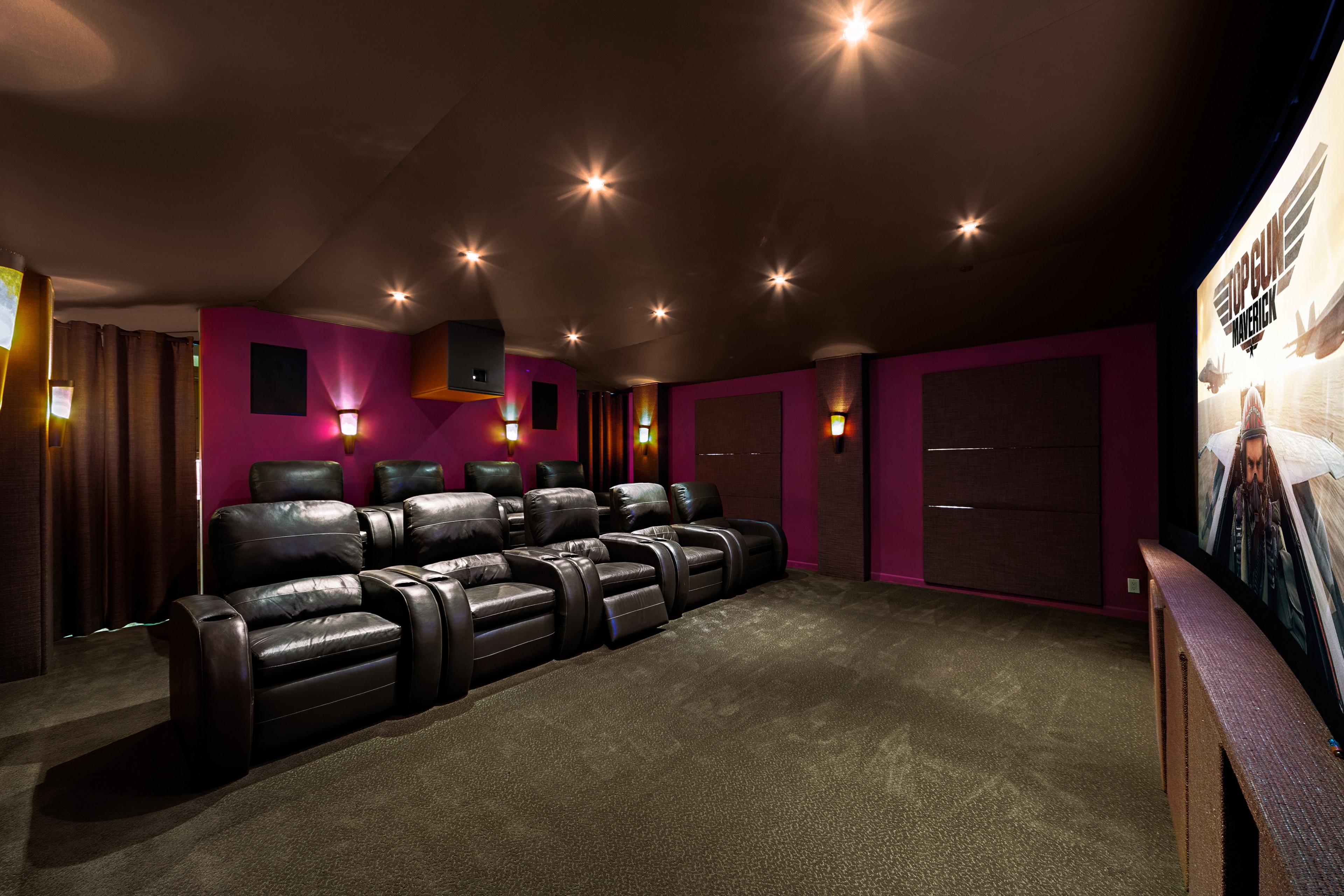 Private media room with leather recliners, magenta walls, and projection screen