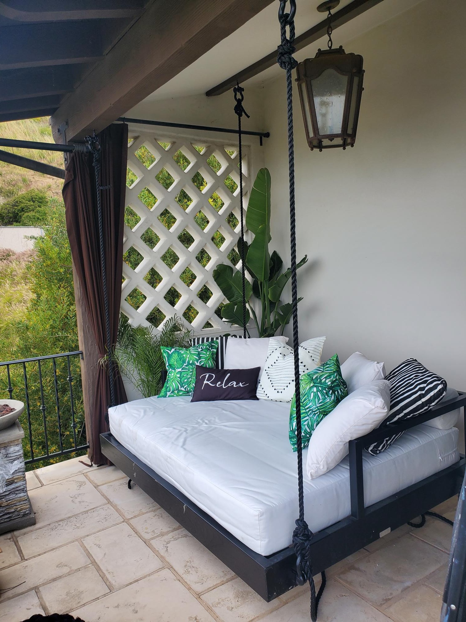 Outdoor swing daybed detail with tropical pillows and rope supports