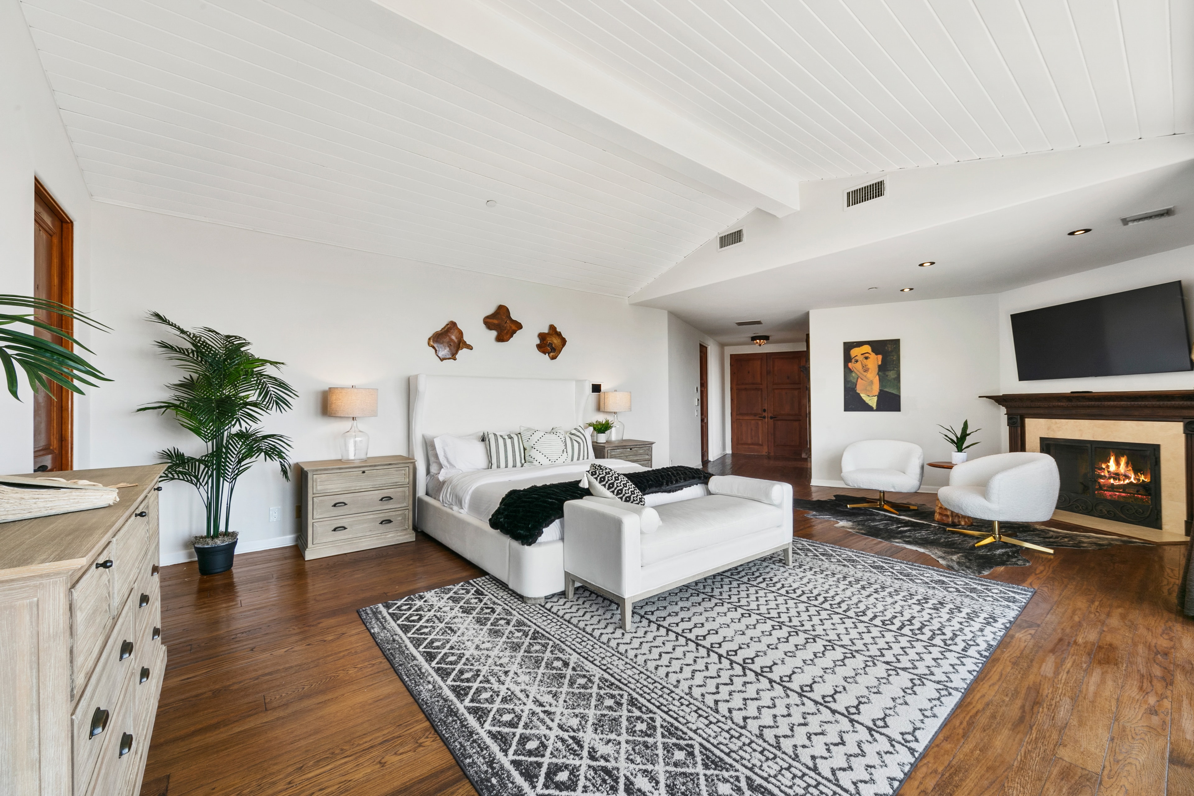 Primary suite with white furnishings, fireplace, and patterned rug