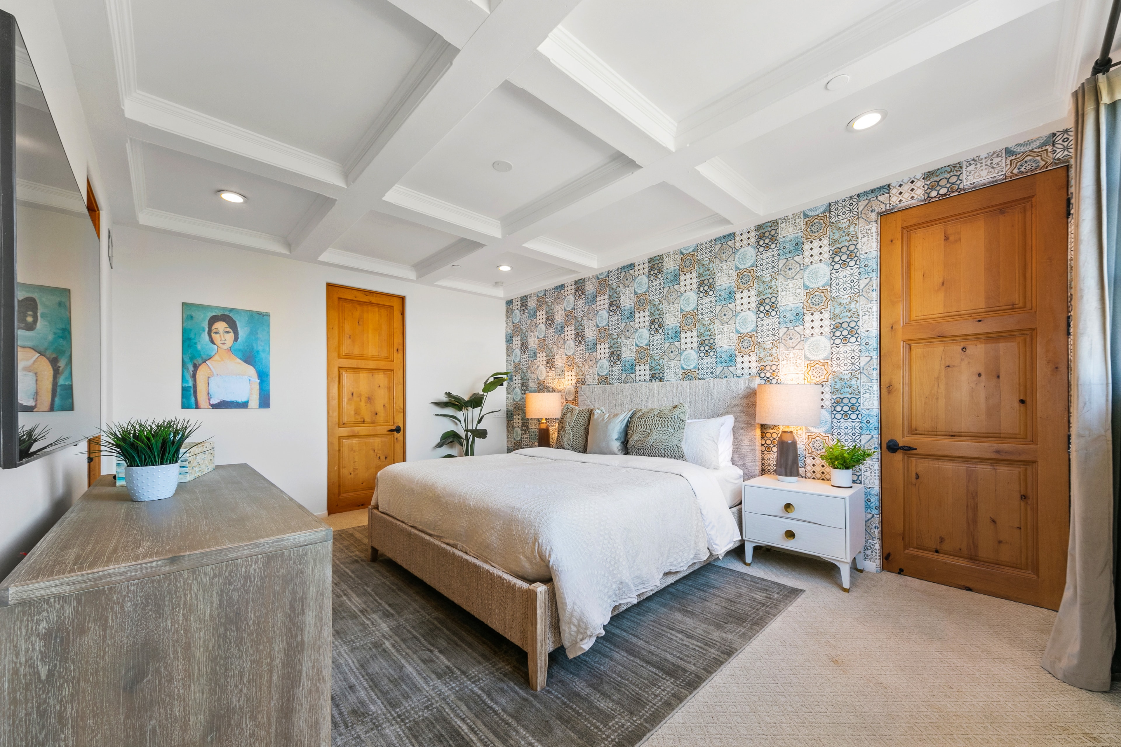 Bedroom with blue patterned tile accent wall and warm wood doors