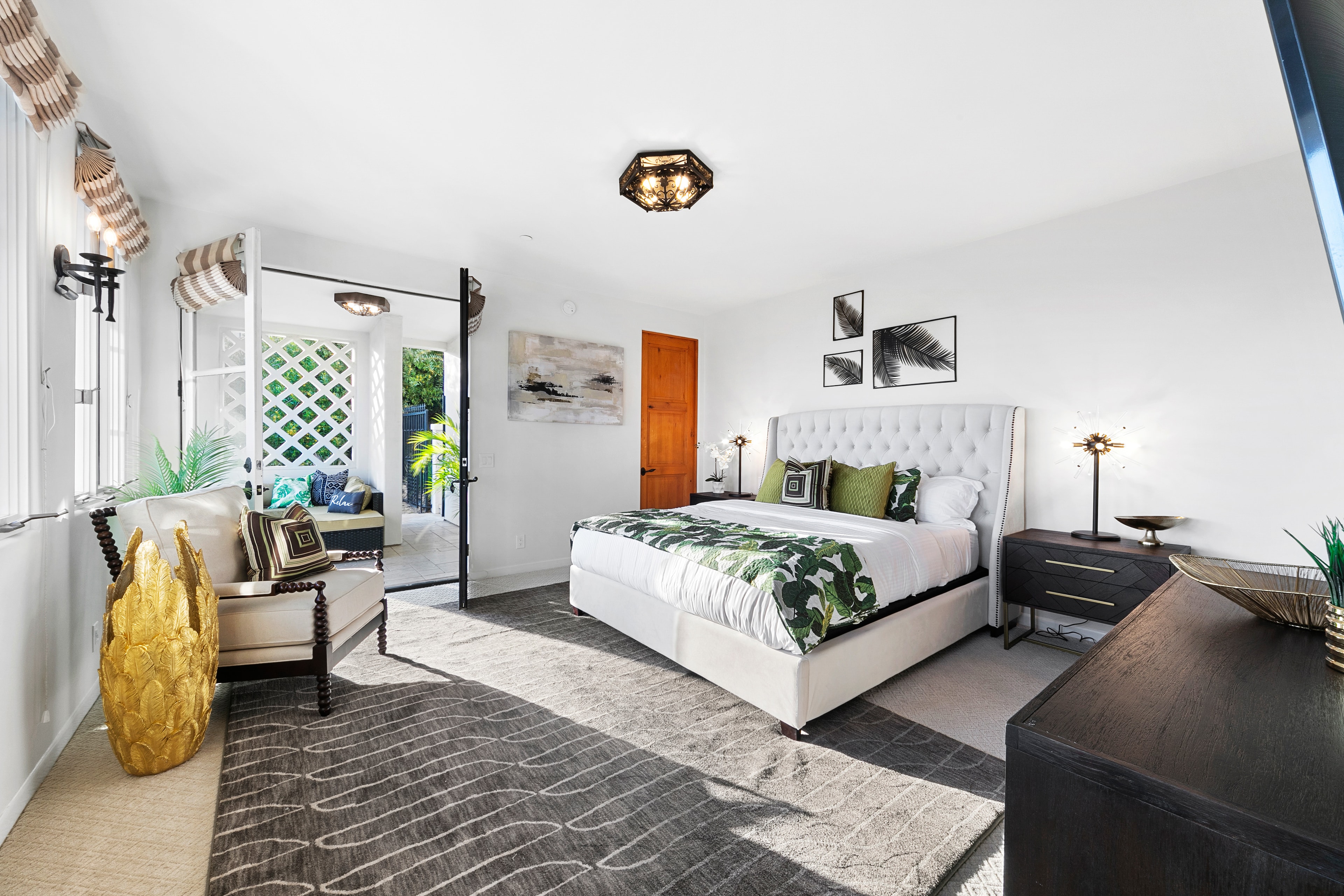 Bright bedroom with tropical bedding, tufted headboard, and garden access