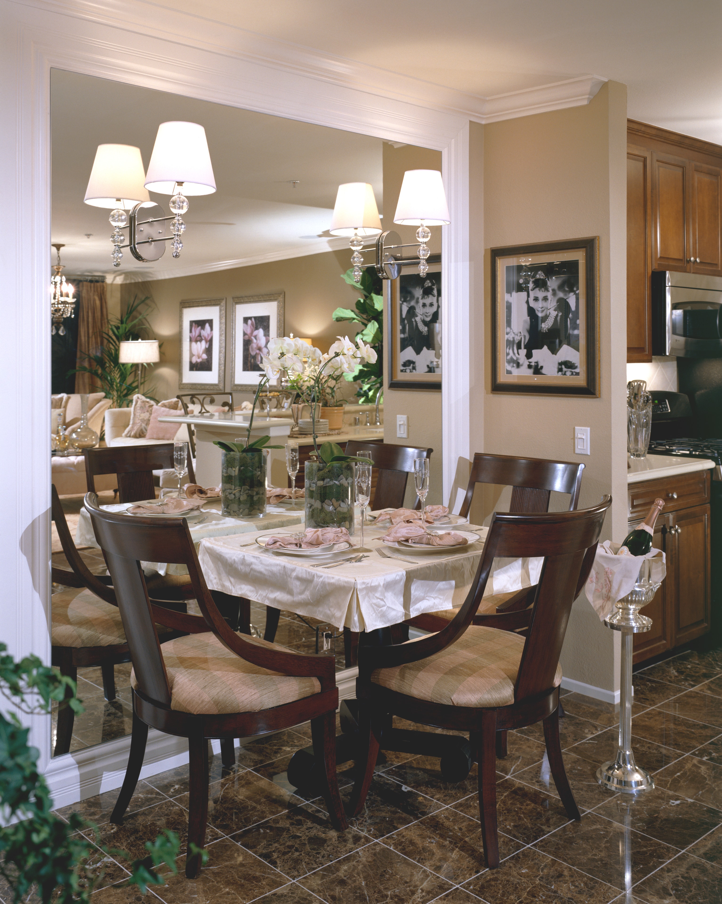 Elegant dining room with mirrored wall, dark wood furniture, and crystal lighting