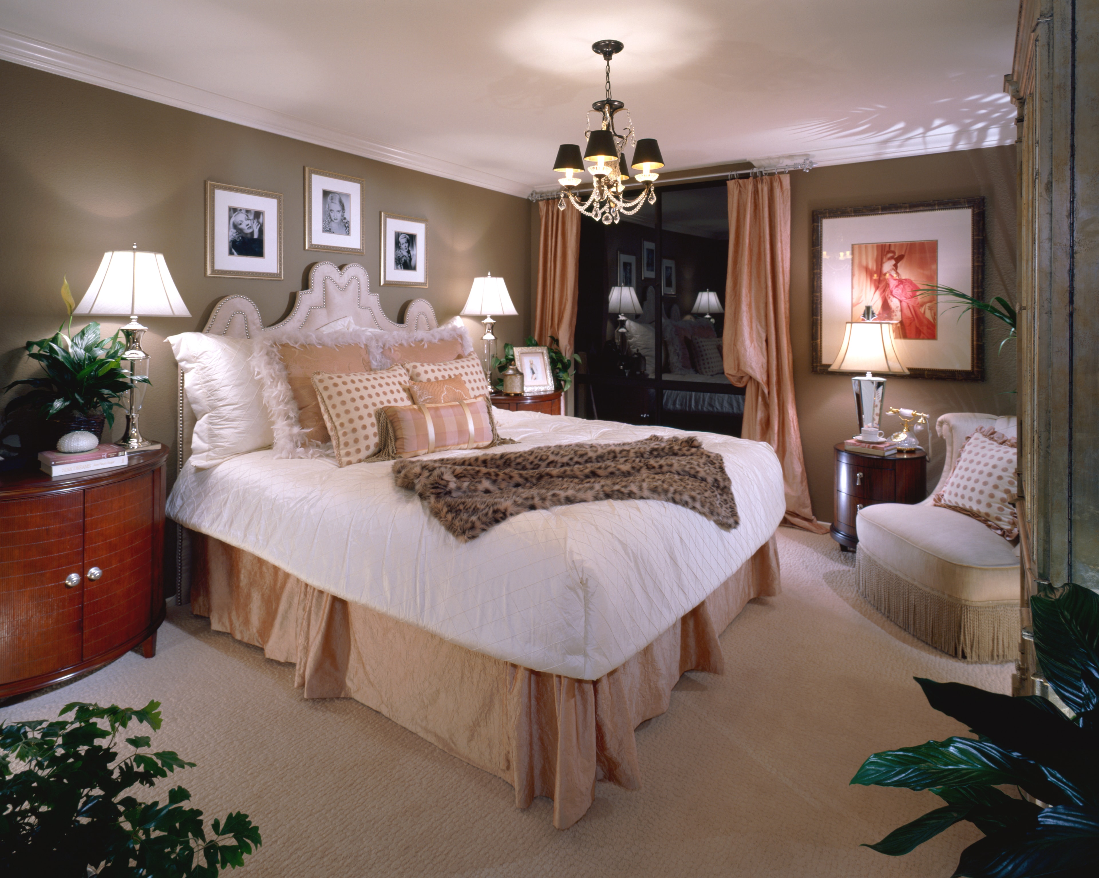 Hollywood glam primary bedroom with a sculptural upholstered bed and crystal chandelier