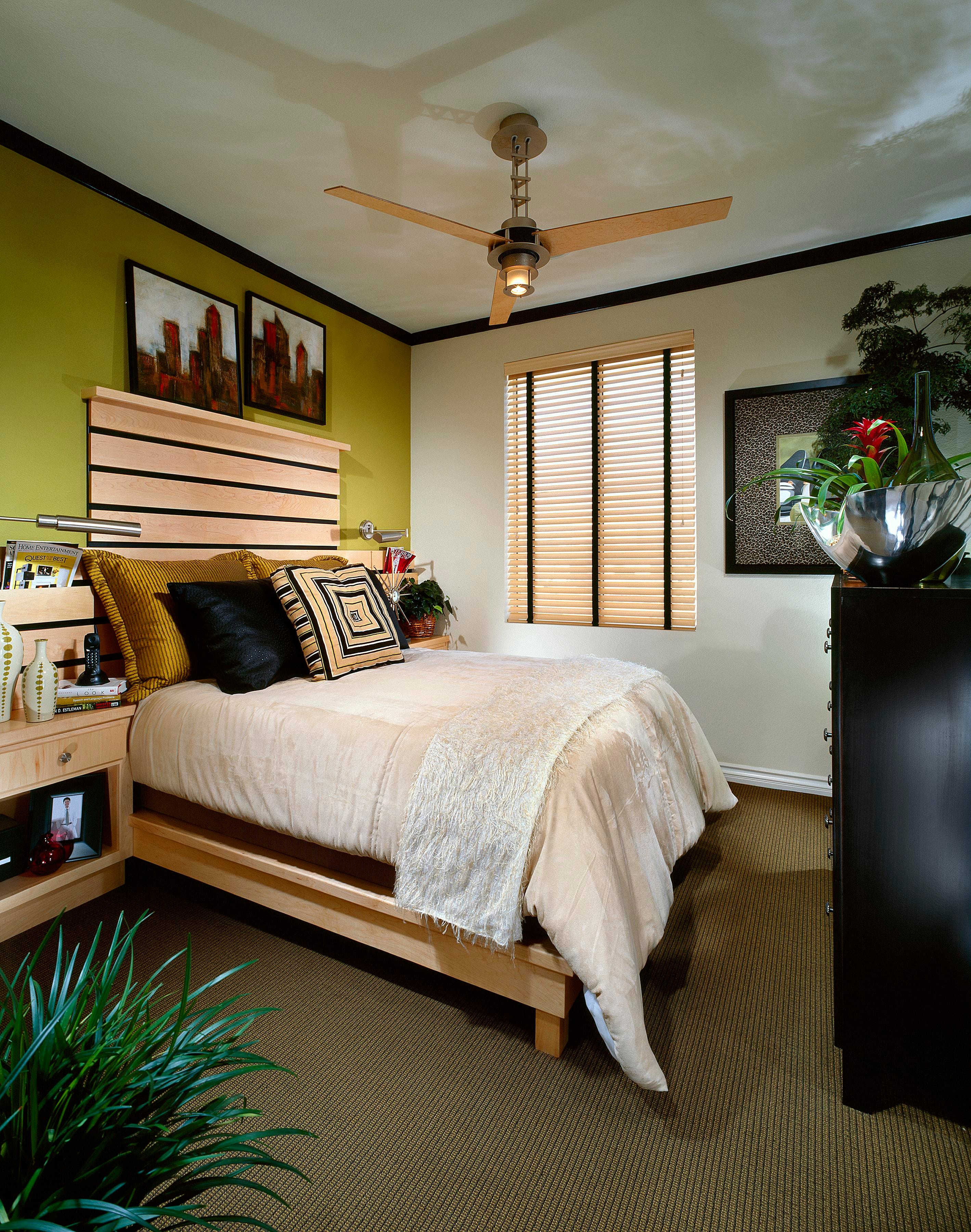 Primary bedroom with maple platform bed, olive accent wall, and tailored black furnishings