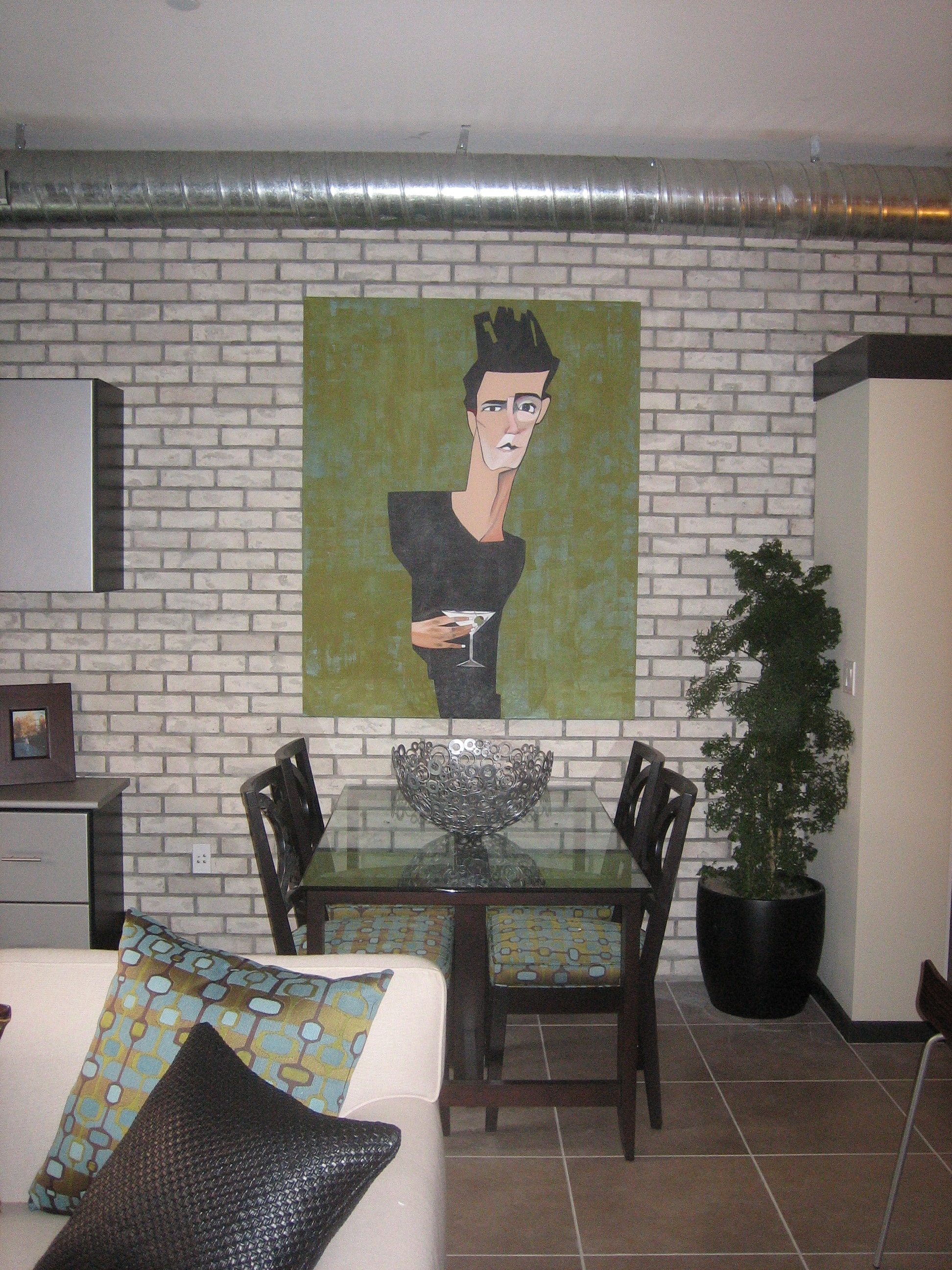Glass dining table against an exposed brick wall with graphic portrait artwork