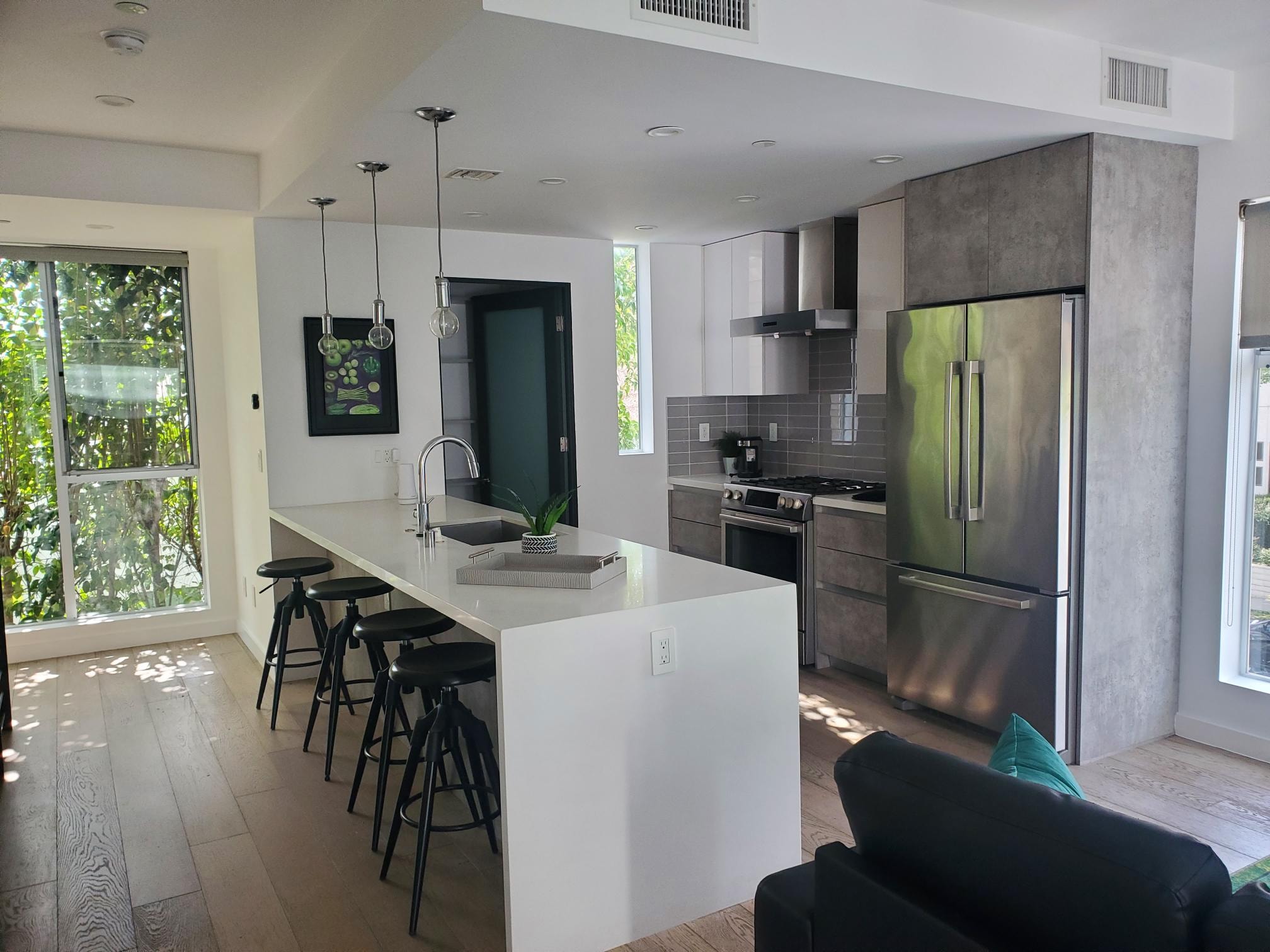 Open kitchen and living area with white island, charcoal sofa, and teal accents