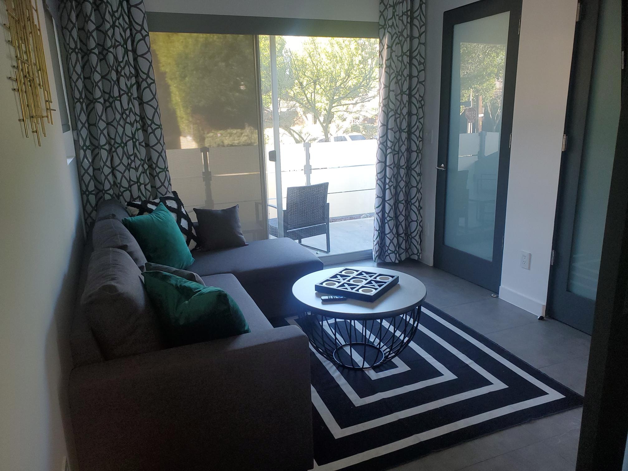 Patio lounge with charcoal sectional, teal pillows, and geometric rug