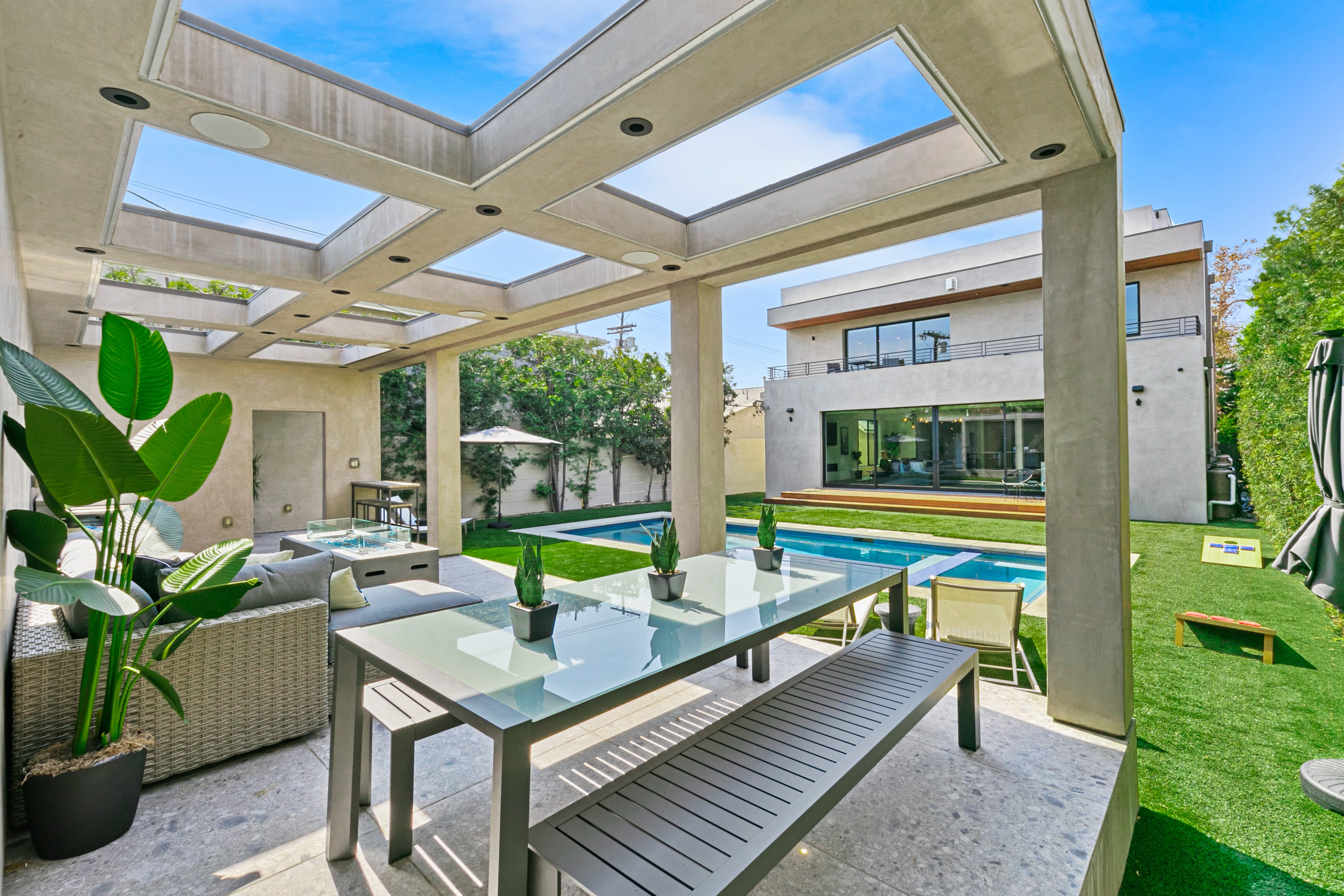 Covered outdoor dining area overlooking the pool and modern home