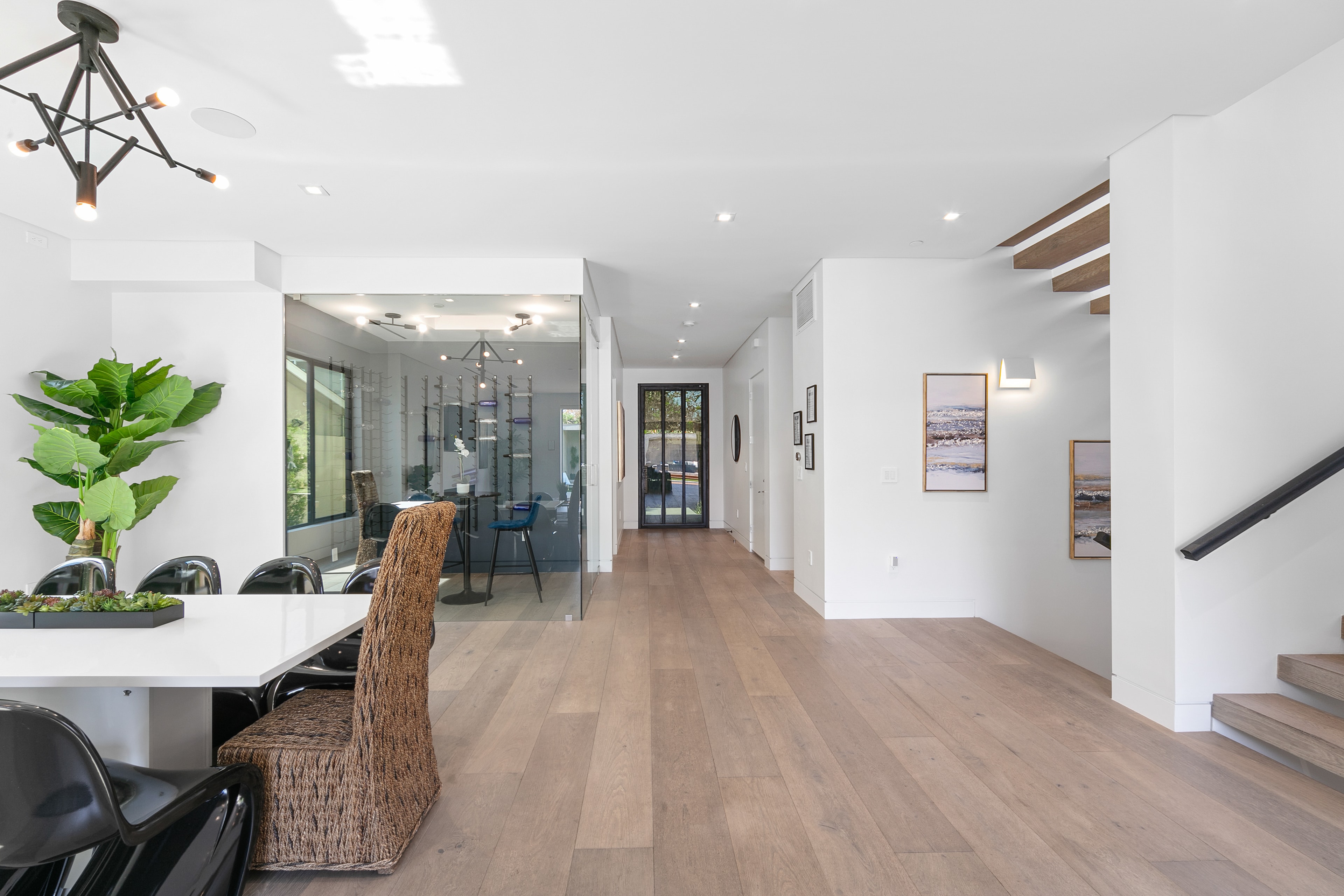 Open-plan dining and entry space with glass wine room and floating staircase