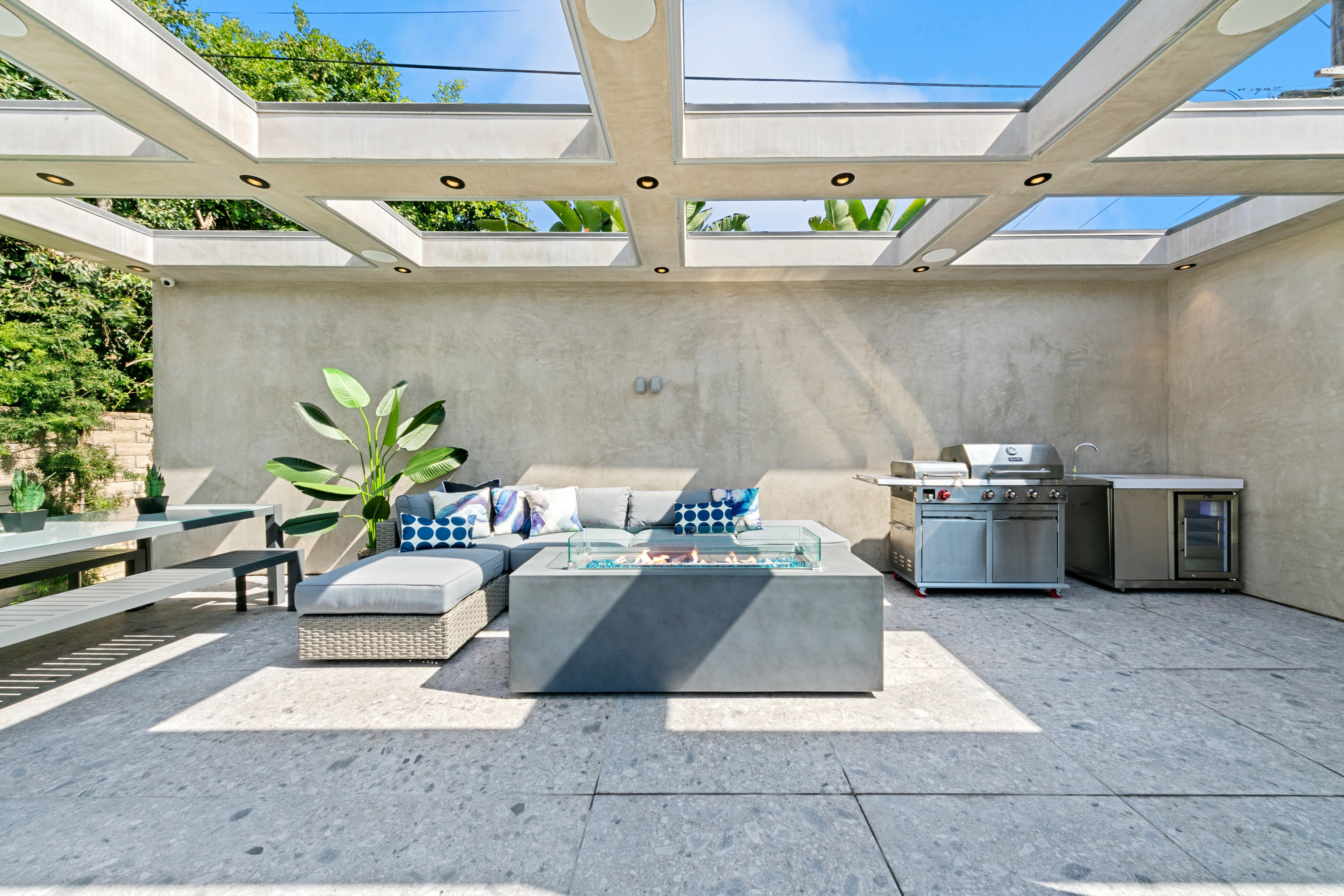 Glass-roof outdoor kitchen and lounge with fire table