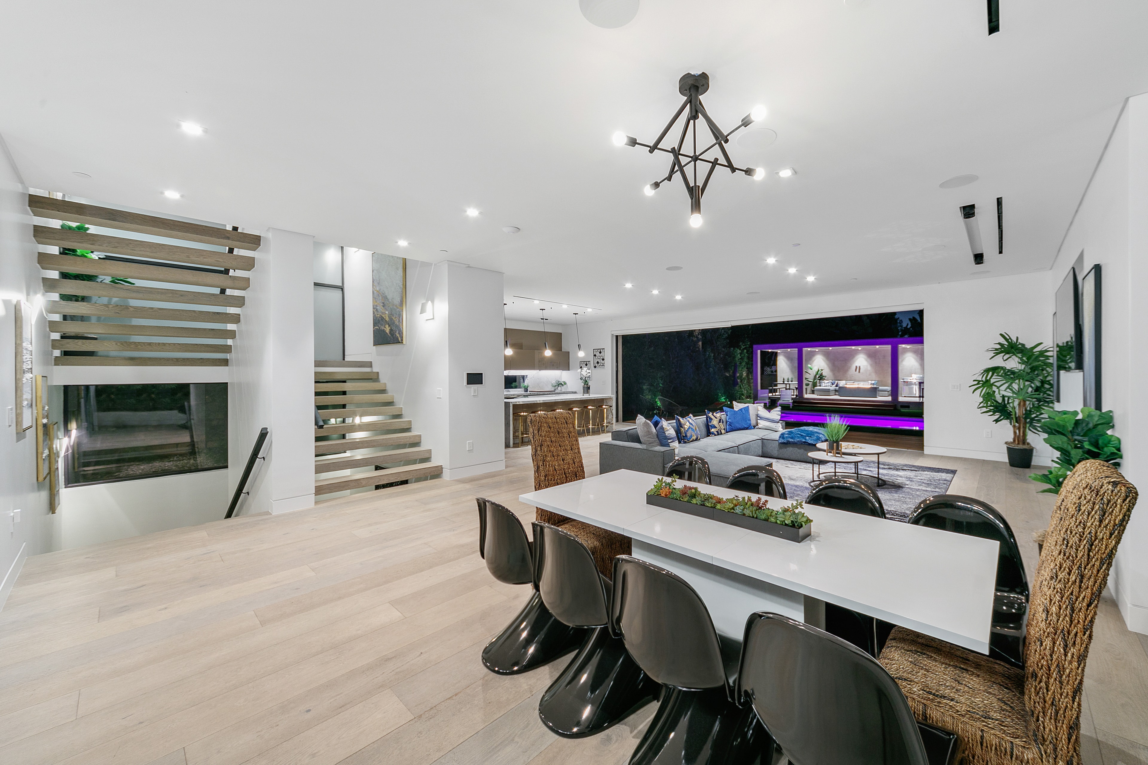 Open-plan dining and living area with illuminated outdoor pavilion at evening
