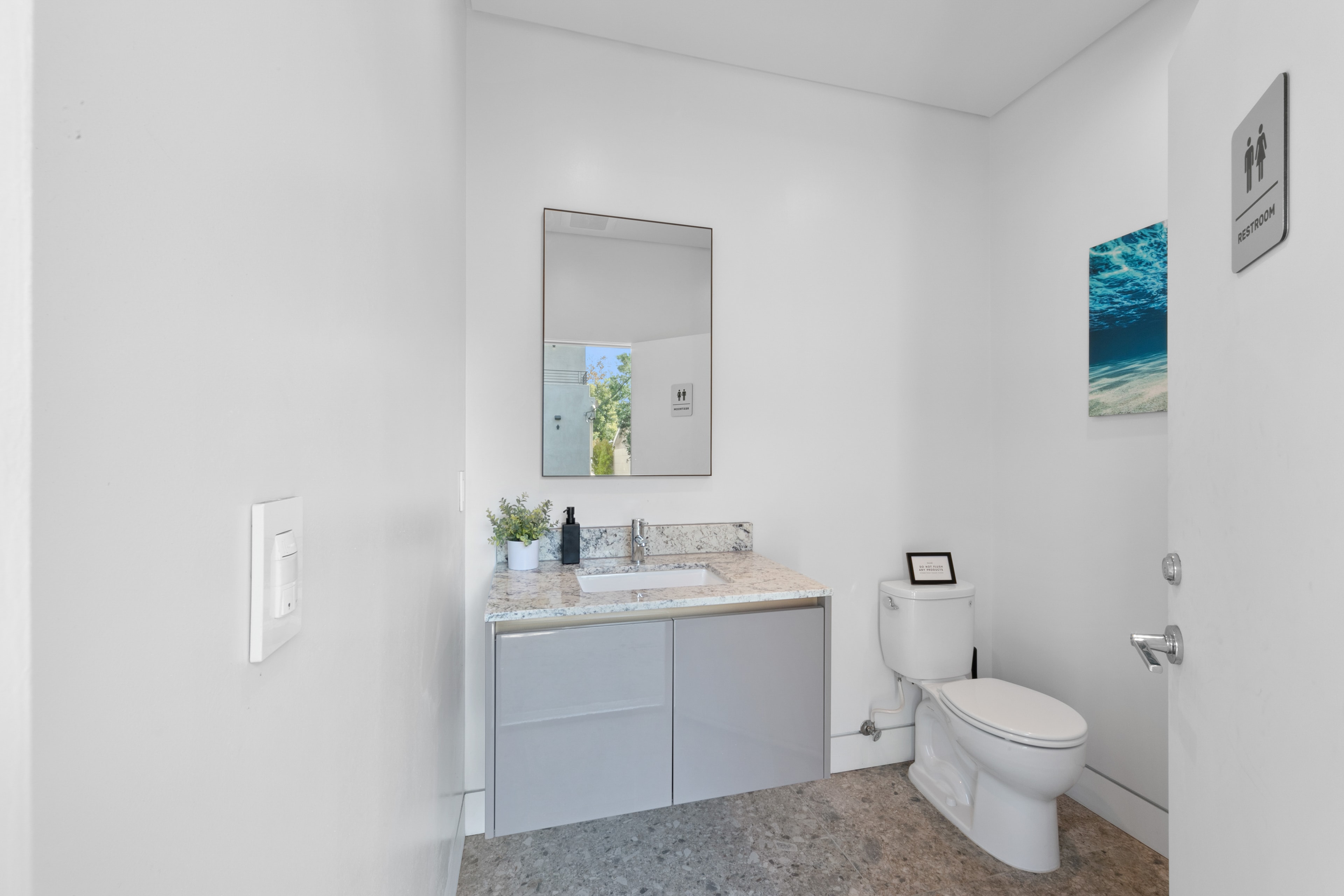 Minimal outdoor bathroom with vanity and ocean artwork
