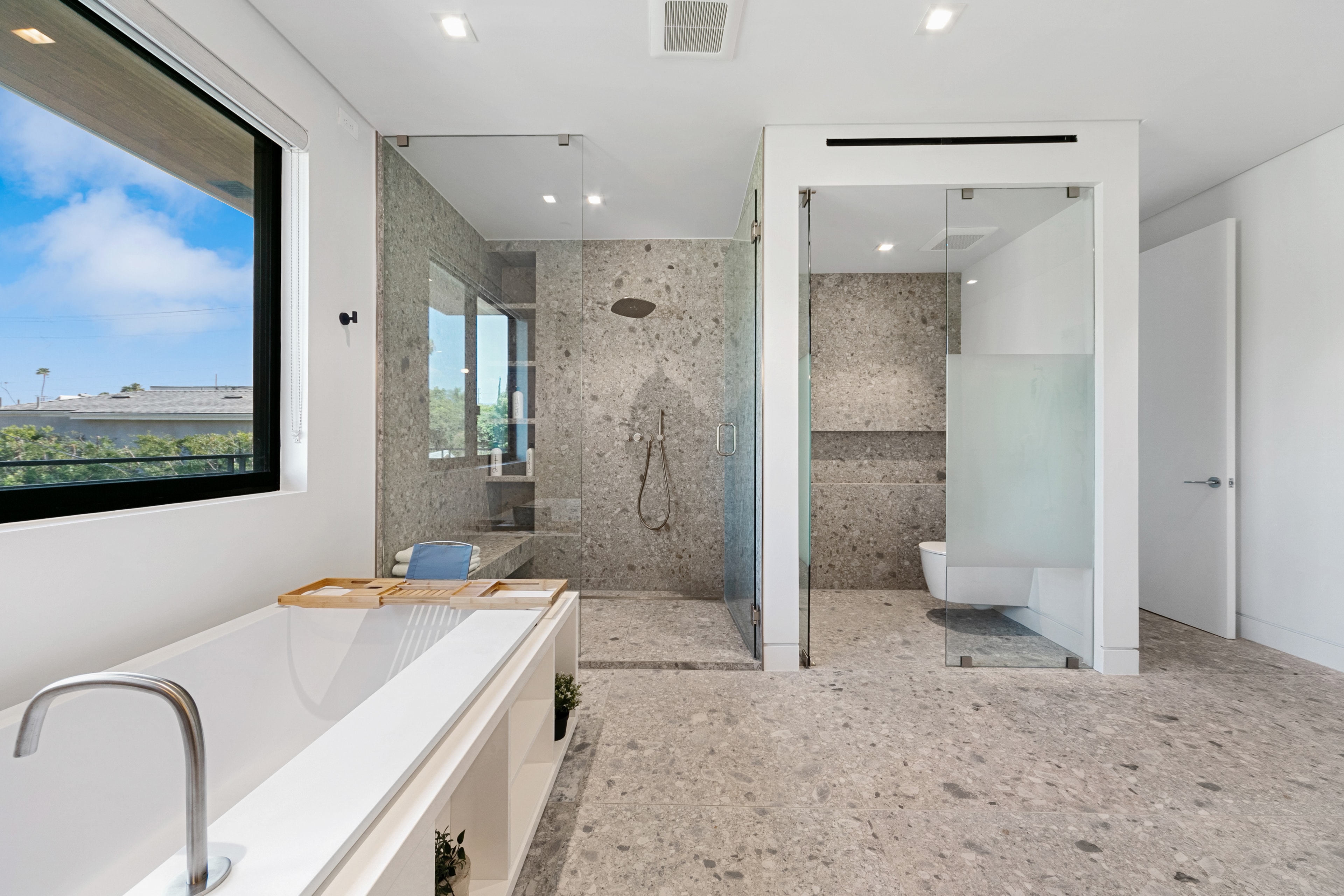 Primary bathroom with stone shower, soaking tub, and glass partitions