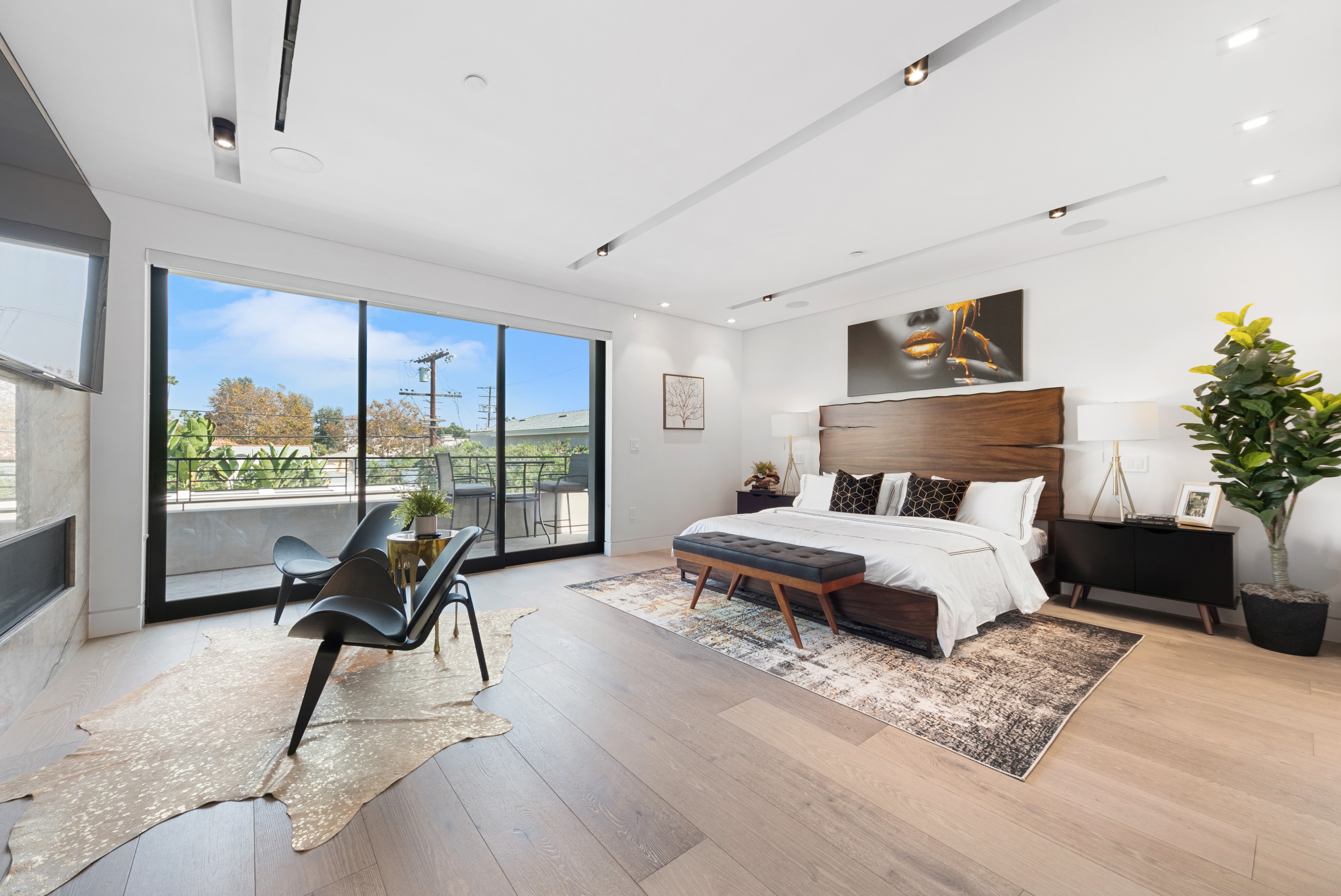 Primary bedroom with contemporary furnishings, balcony, and large windows