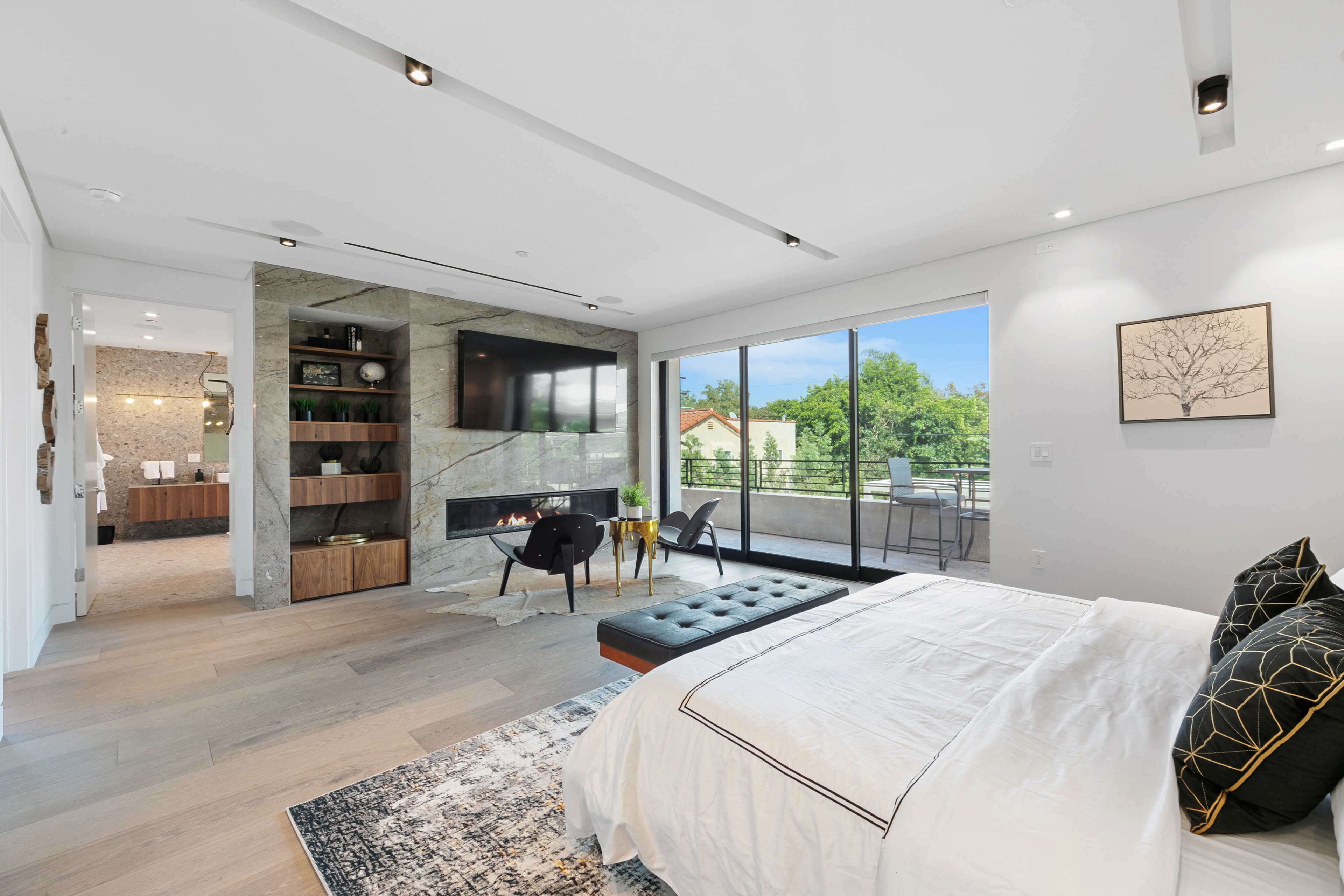 Primary suite with marble fireplace wall, balcony, and sitting area