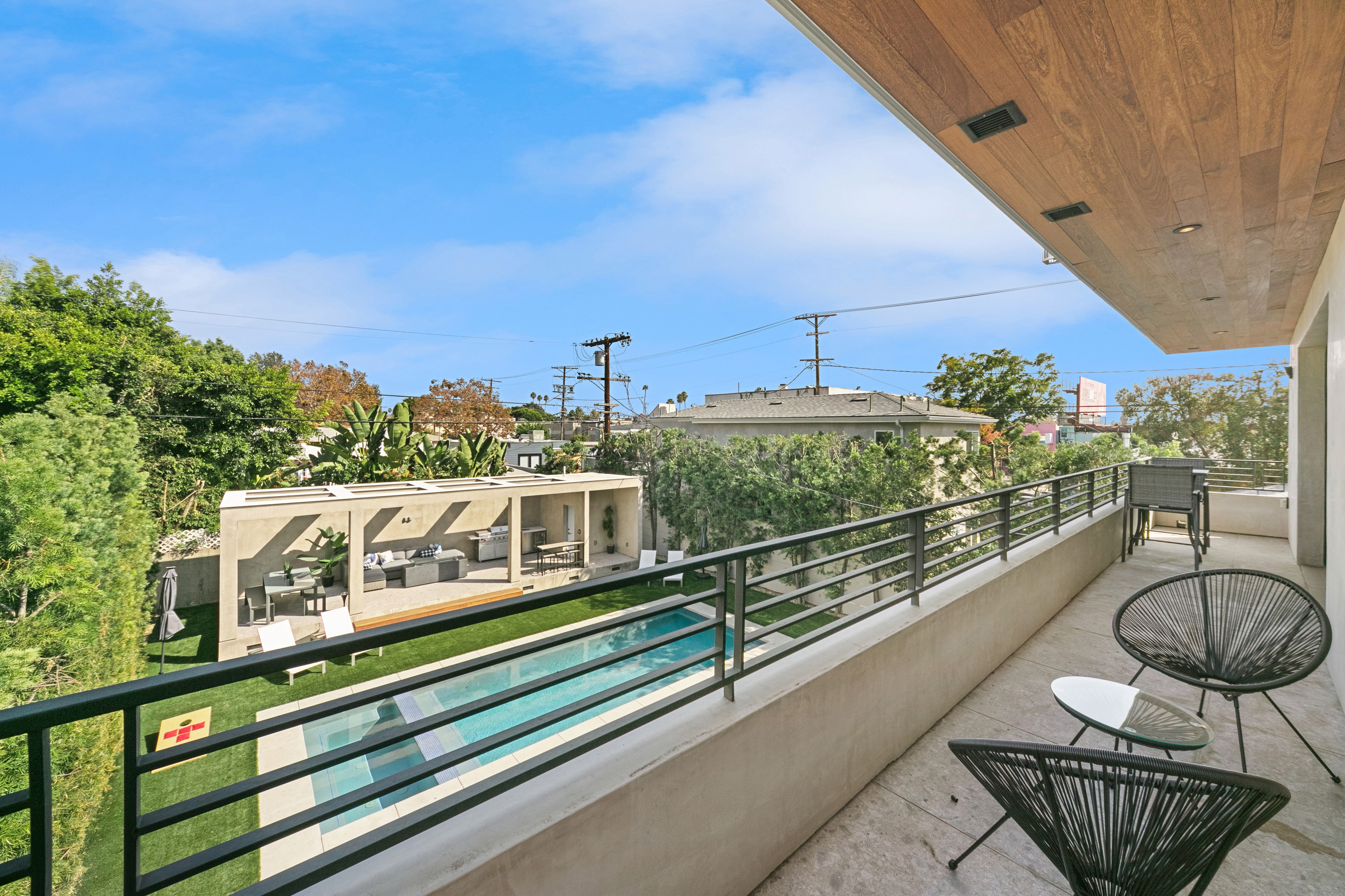 Primary-suite balcony overlooking the pool, outdoor pavilion, and landscaped backyard