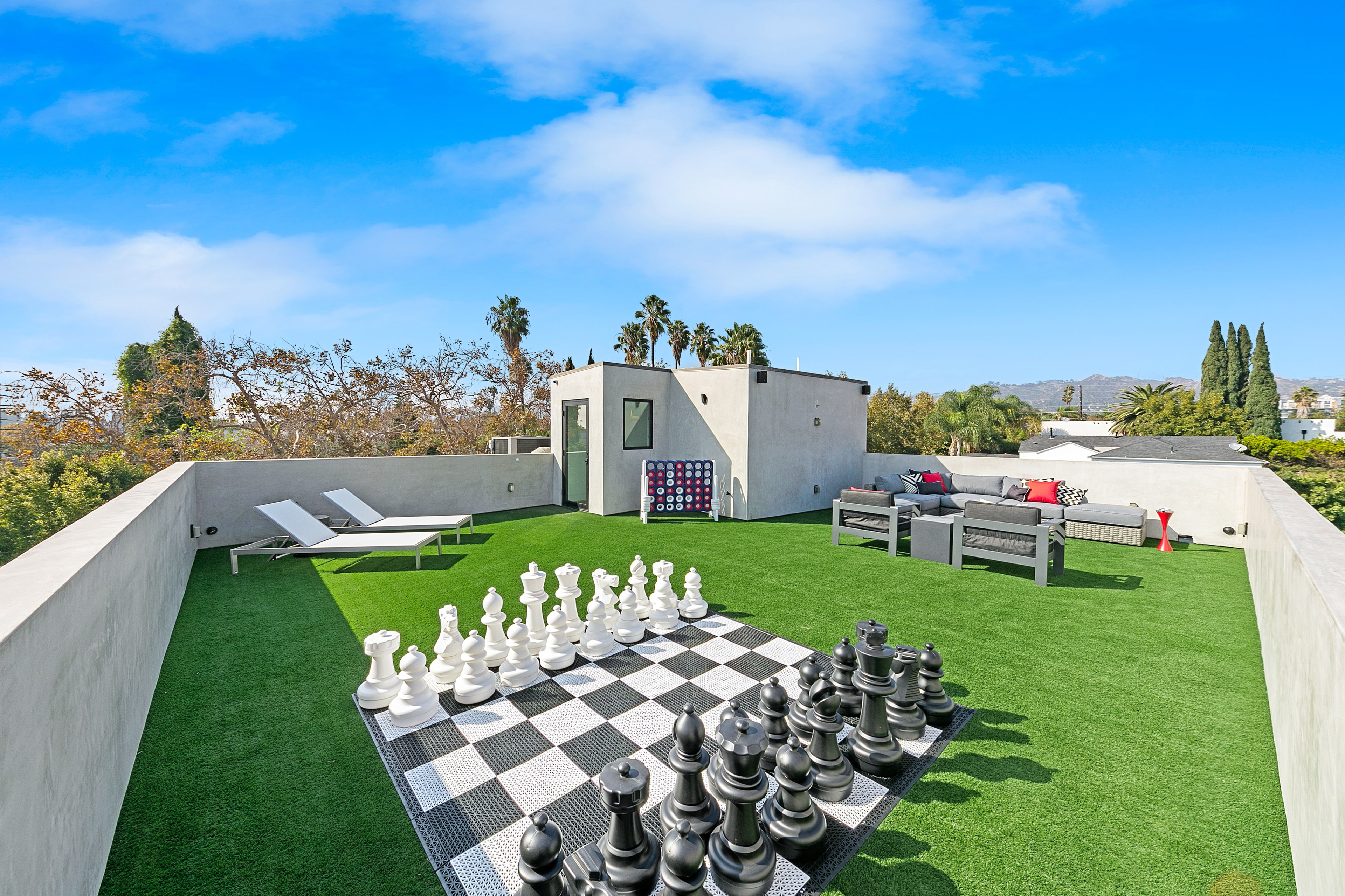 Expansive rooftop terrace with oversized chess, lounge seating, and mountain views