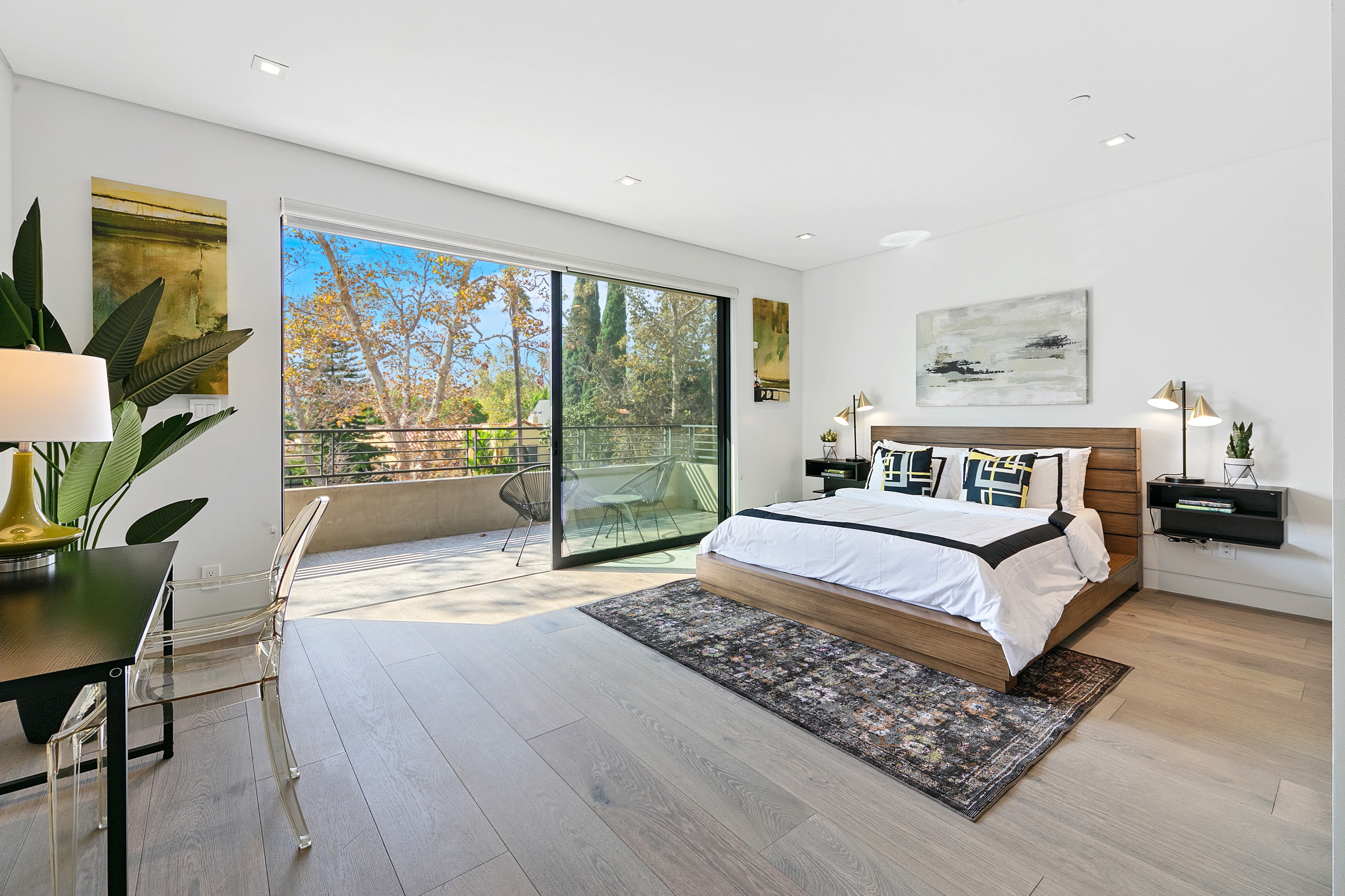 Bright upstairs bedroom with wood furnishings, artwork, and balcony access