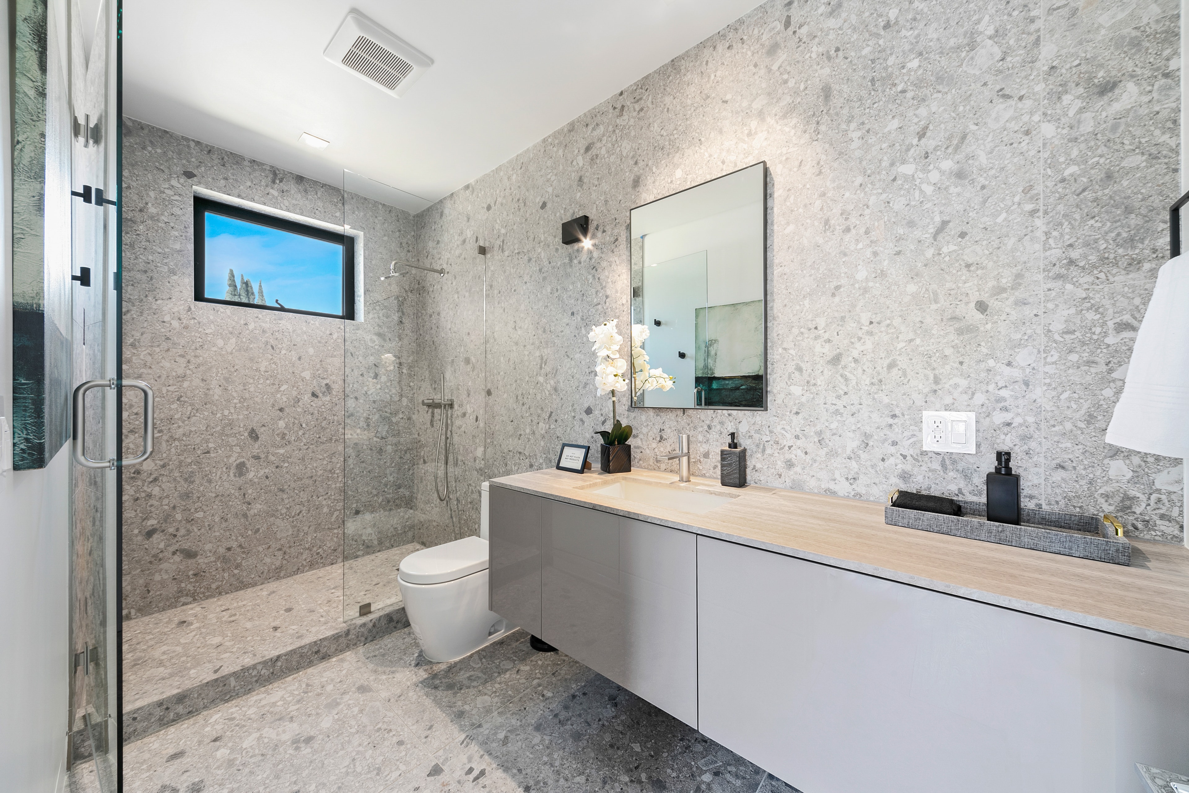 Modern gray stone bathroom with glass shower and floating vanity