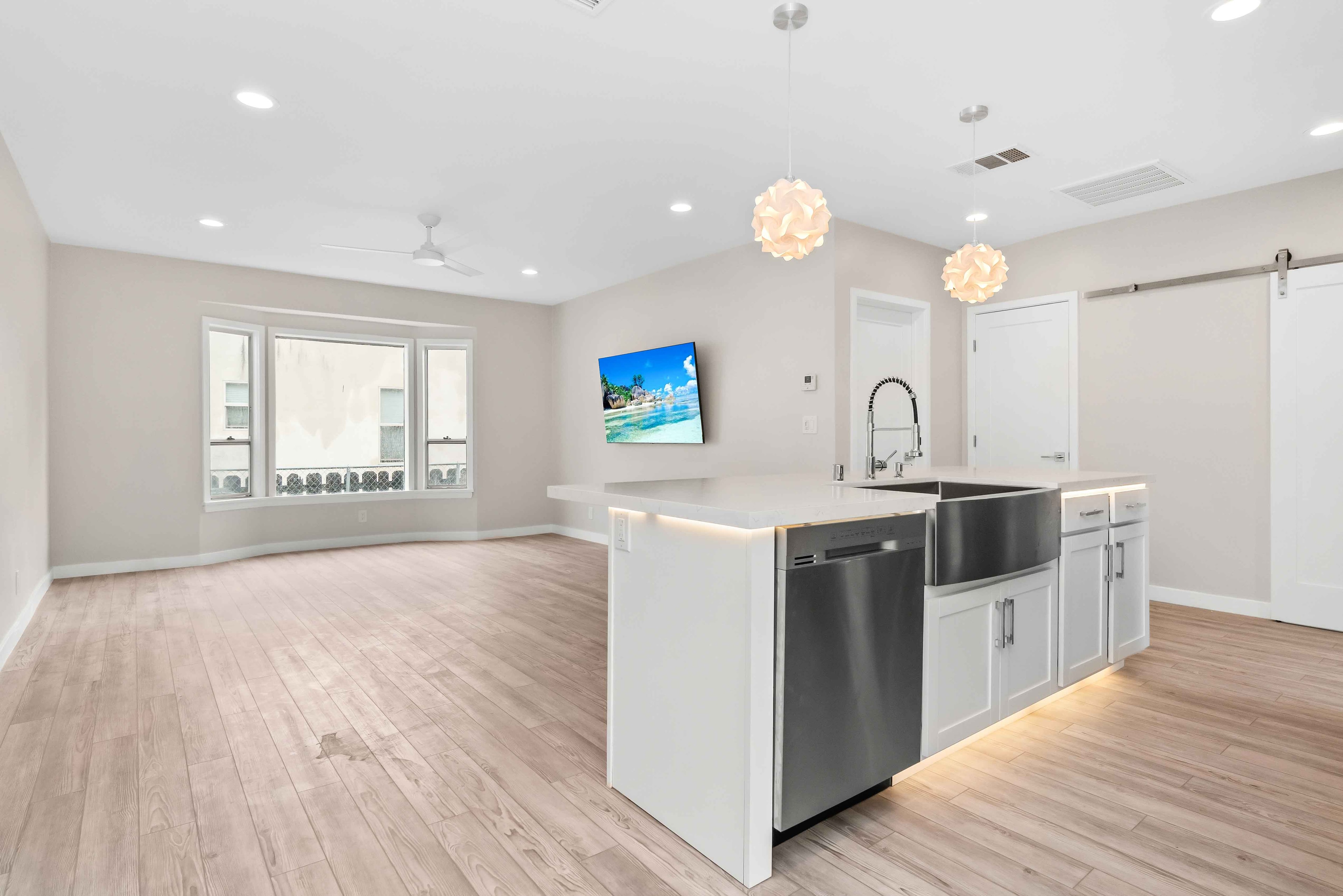 Open-plan kitchen and living room with white island and bay window