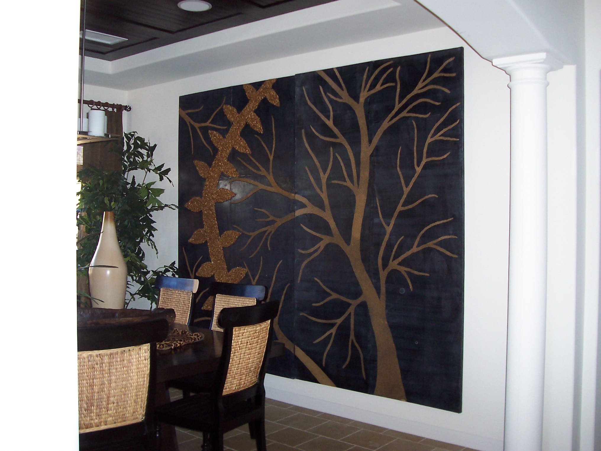 Dining area with large botanical wall artwork and woven chairs
