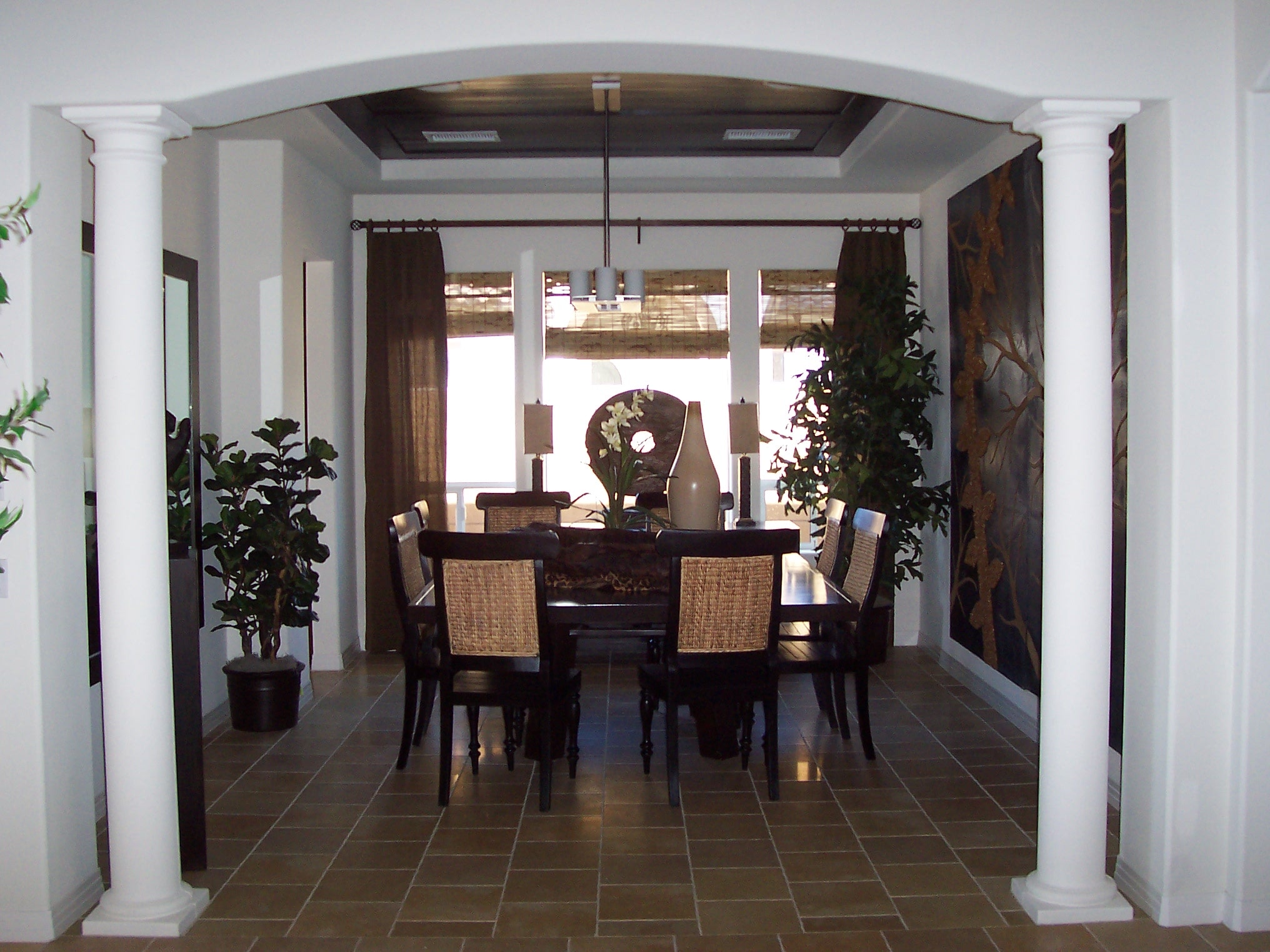 Columned dining room with dark wood table and natural woven chairs