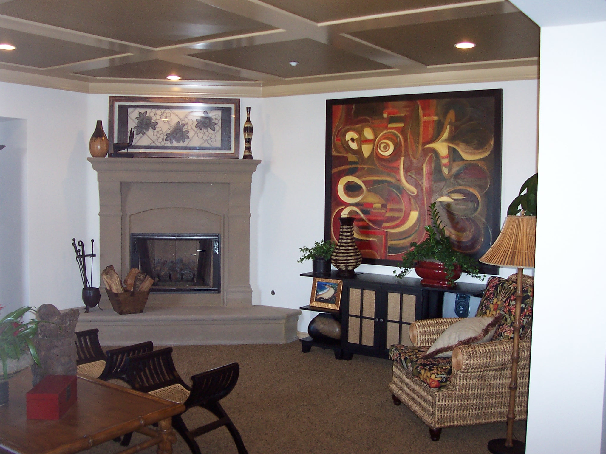 Living room fireplace with abstract artwork and woven accent chair