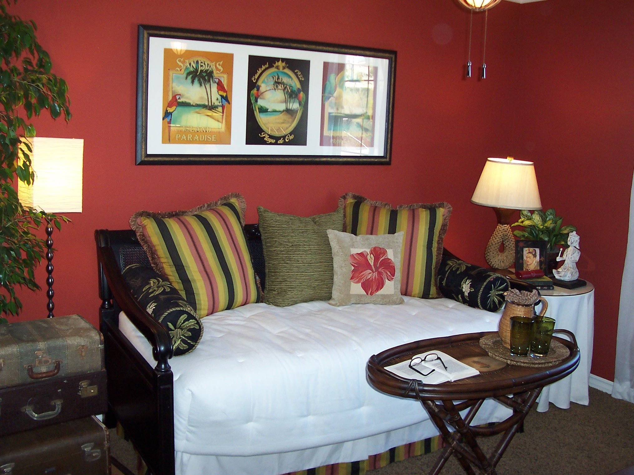Red-walled daybed nook with tropical artwork and striped cushions